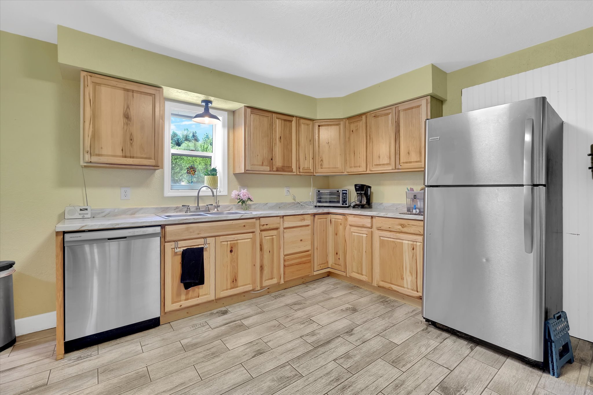 Kitchen featuring natural wood cabinetry, light-toned countertops, and wood-finish tile flooring