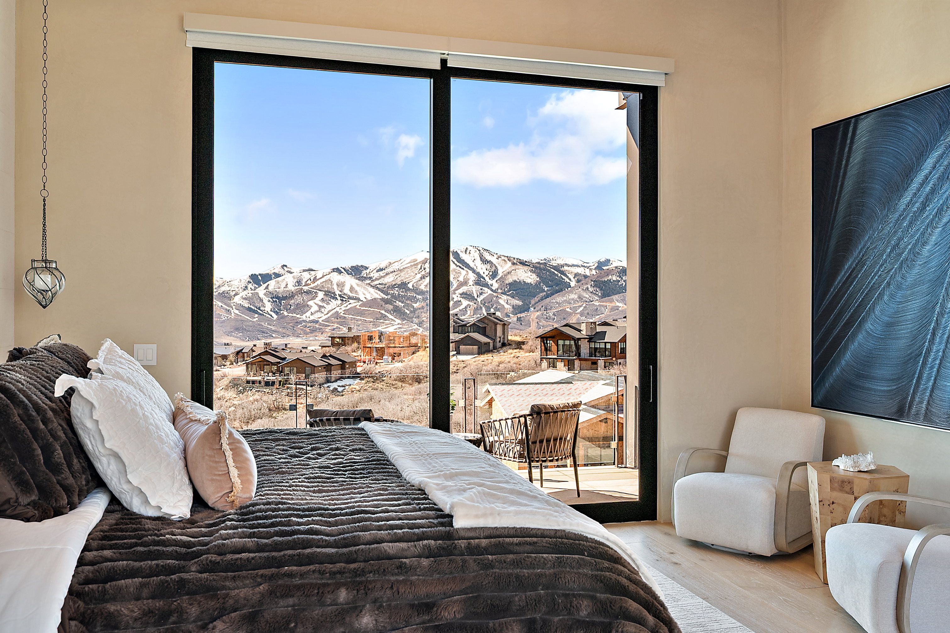 Room featuring floor-to-ceiling sliding glass doors, a mountain backdrop, a balcony, and light wood-finish flooring