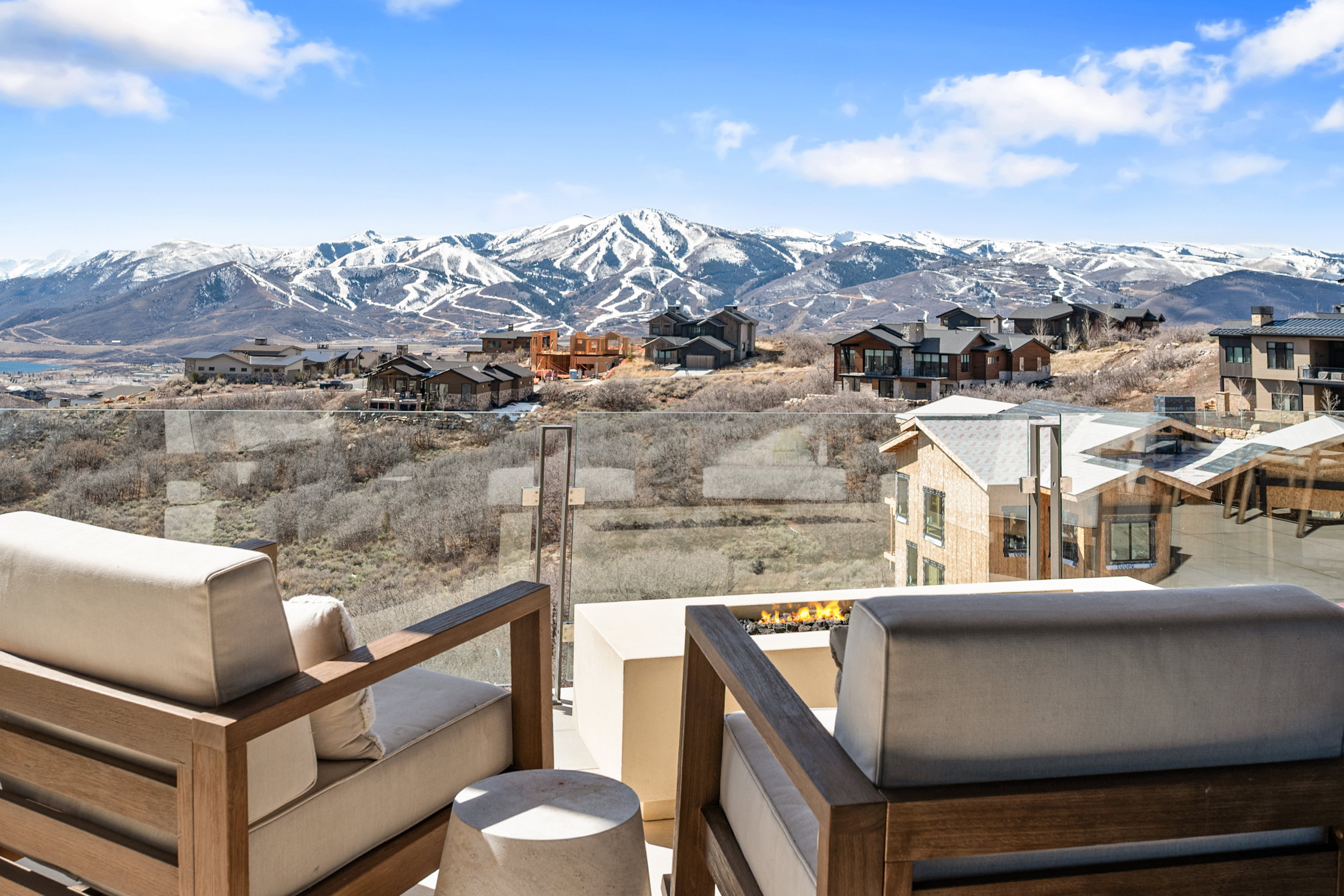 Outdoor living space featuring a glass railing, a built-in fire pit, and expansive mountain scenery