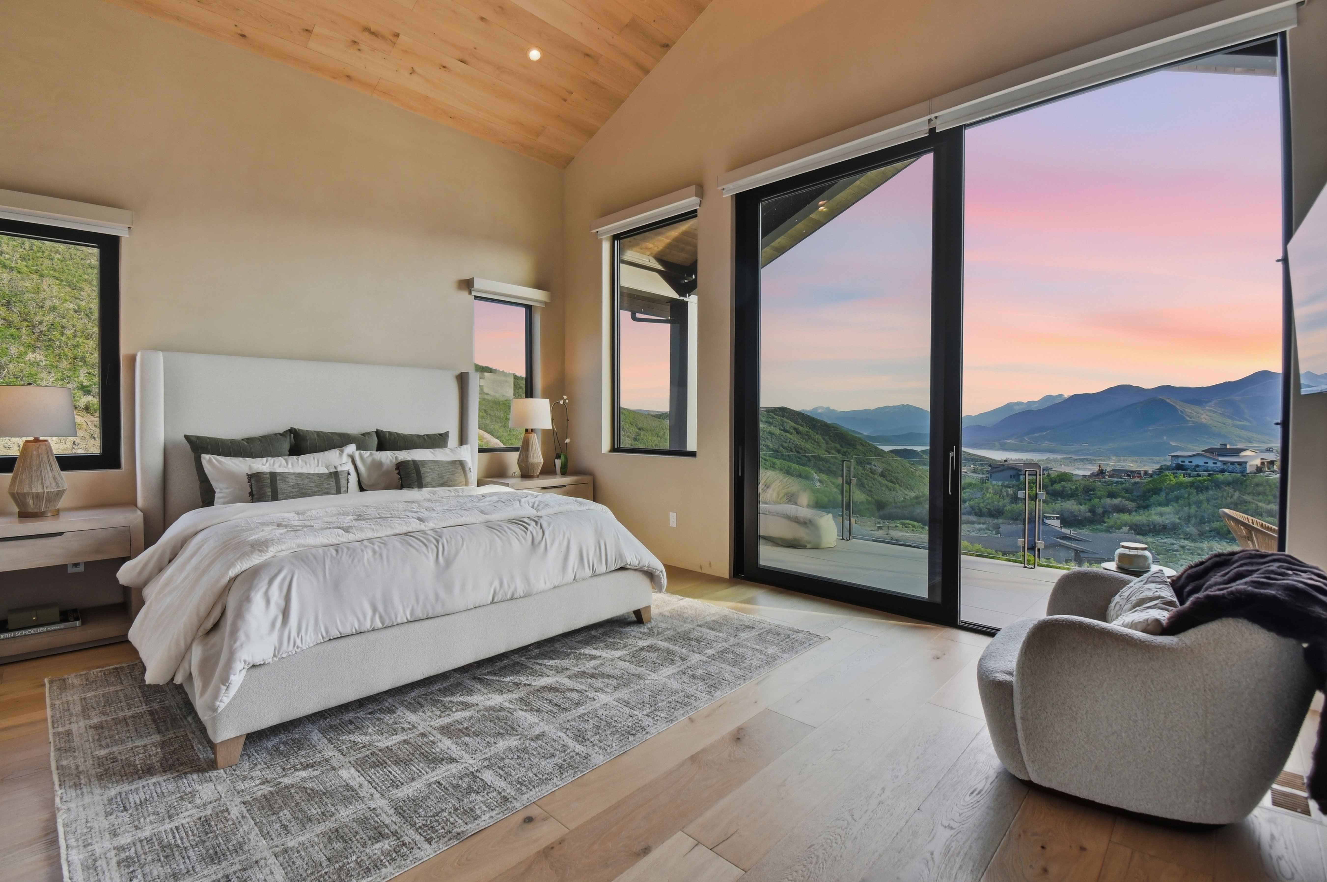 Bedroom featuring a vaulted wood-paneled ceiling, light wood-finish flooring, and expansive sliding glass doors opening to a scenic mountain landscape