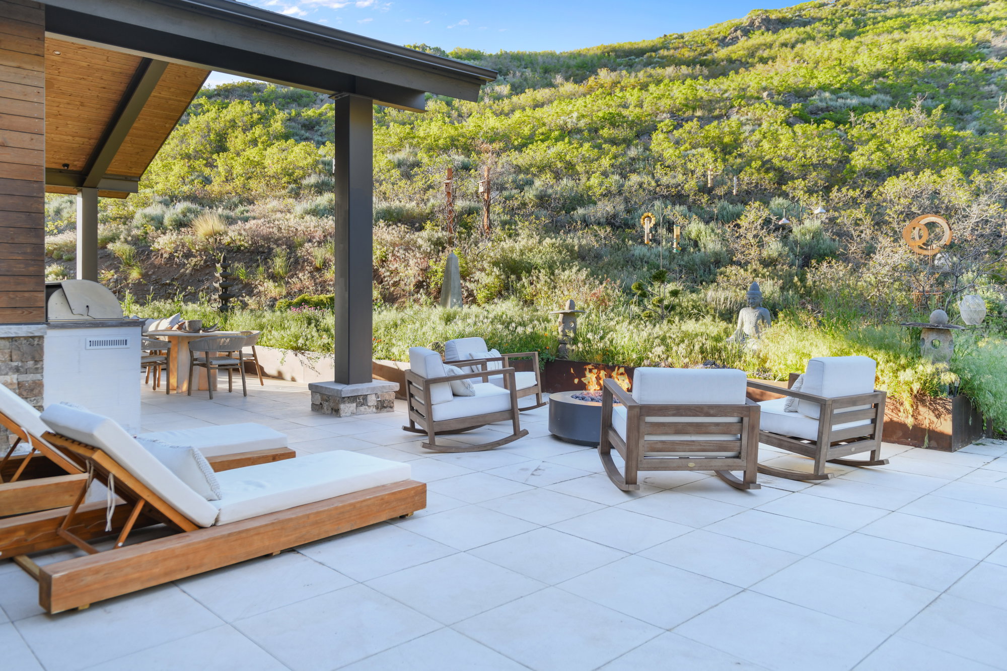 Expansive outdoor patio featuring a built-in grill station, covered dining area, and a fire pit