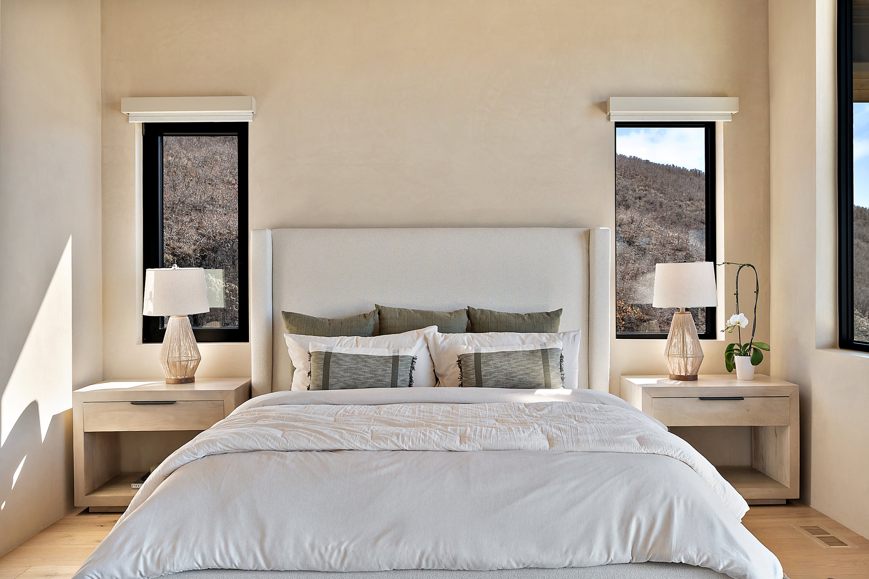 Bedroom featuring light-toned walls, light wood-finish flooring, and recessed baseboard registers