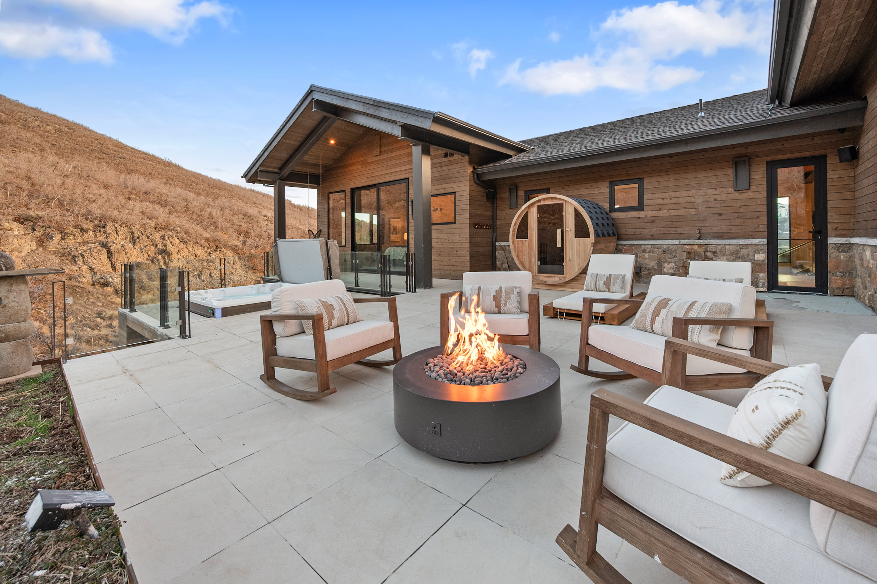 Expansive outdoor patio featuring a fire pit, hot tub, and barrel sauna