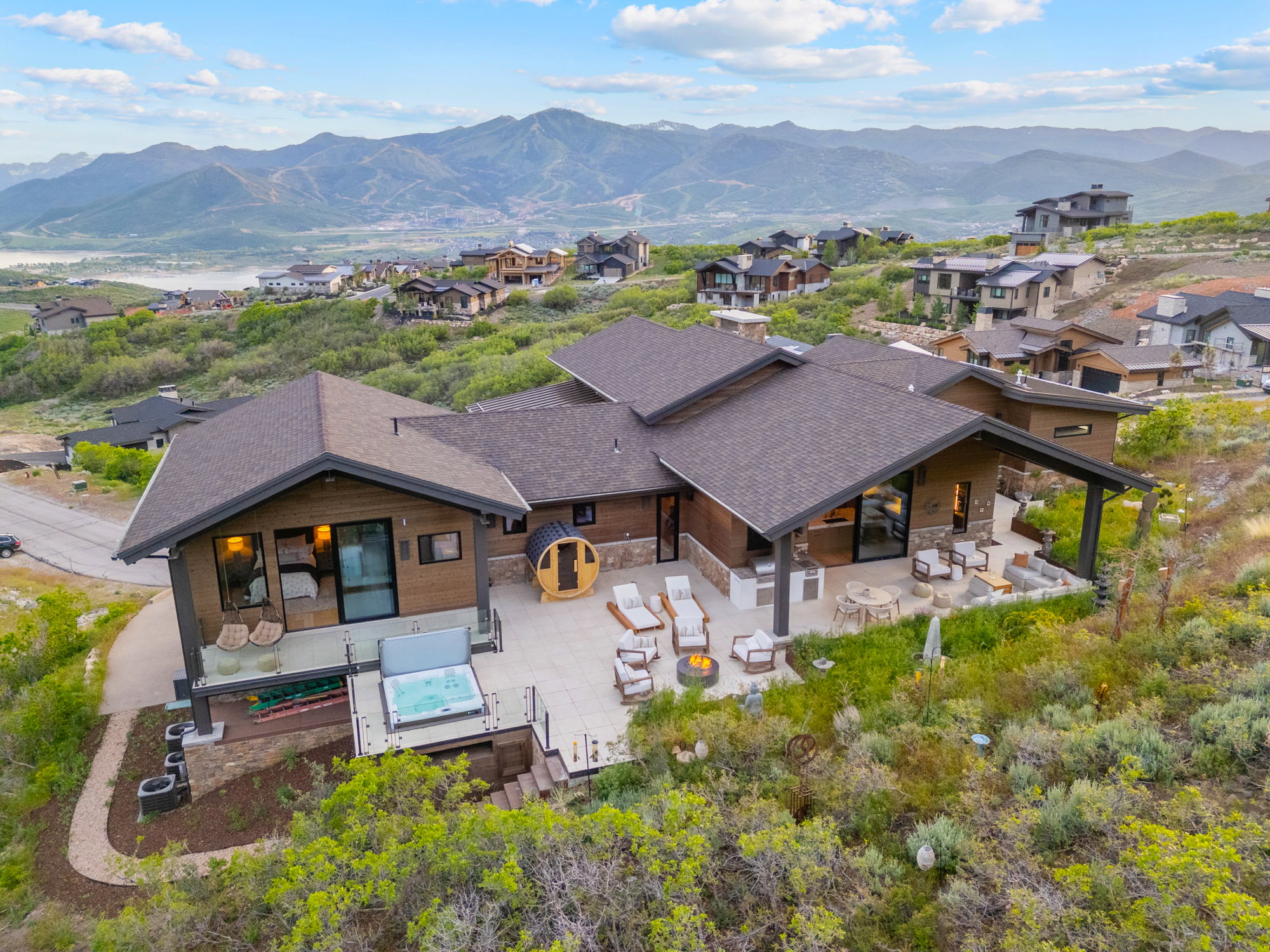 Contemporary mountain home featuring expansive multi-level outdoor living spaces, a covered patio, a hot tub, and a barrel sauna