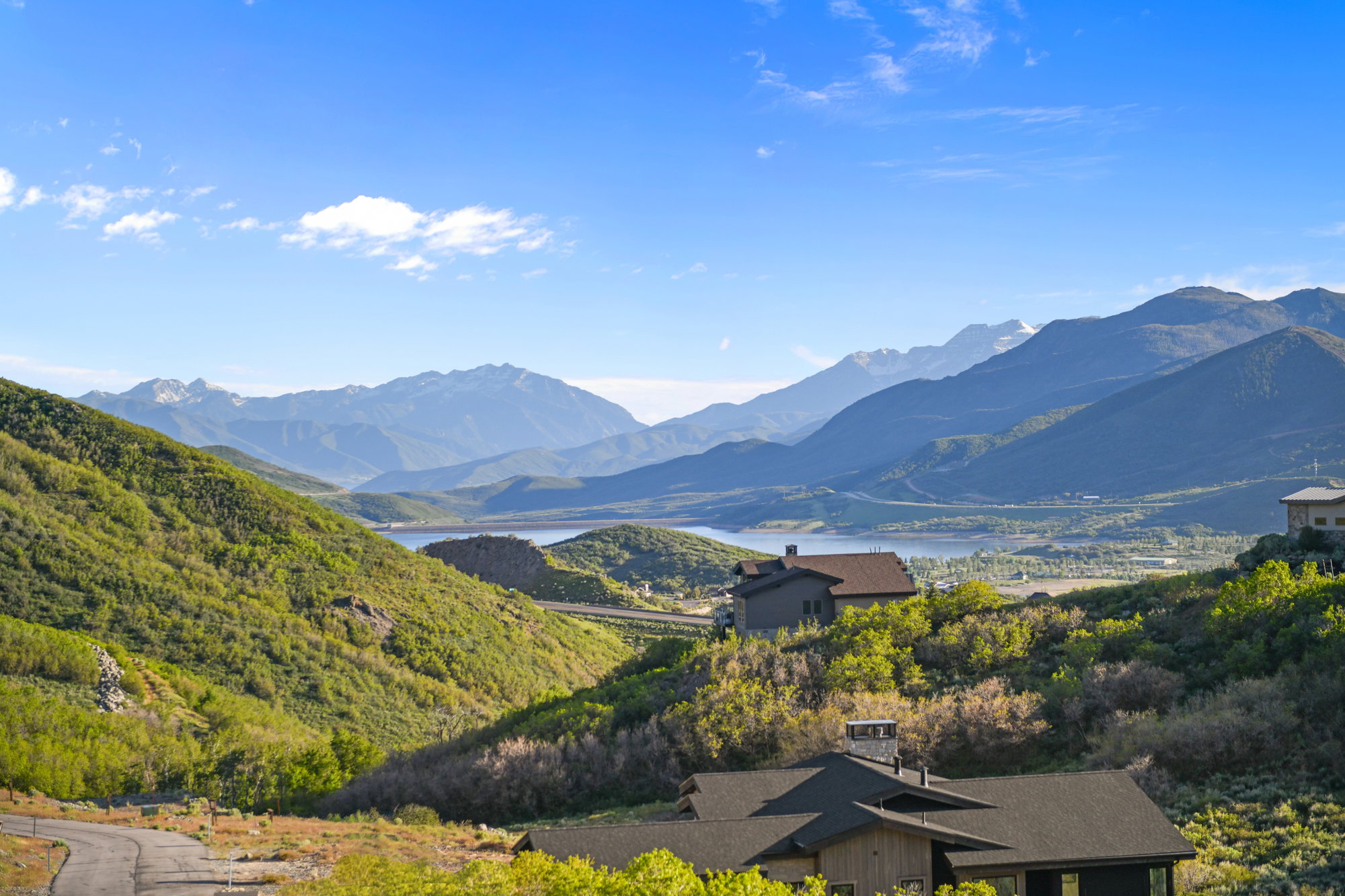 Mountainous landscape featuring a lake, surrounded by green hillsides and distant peaks