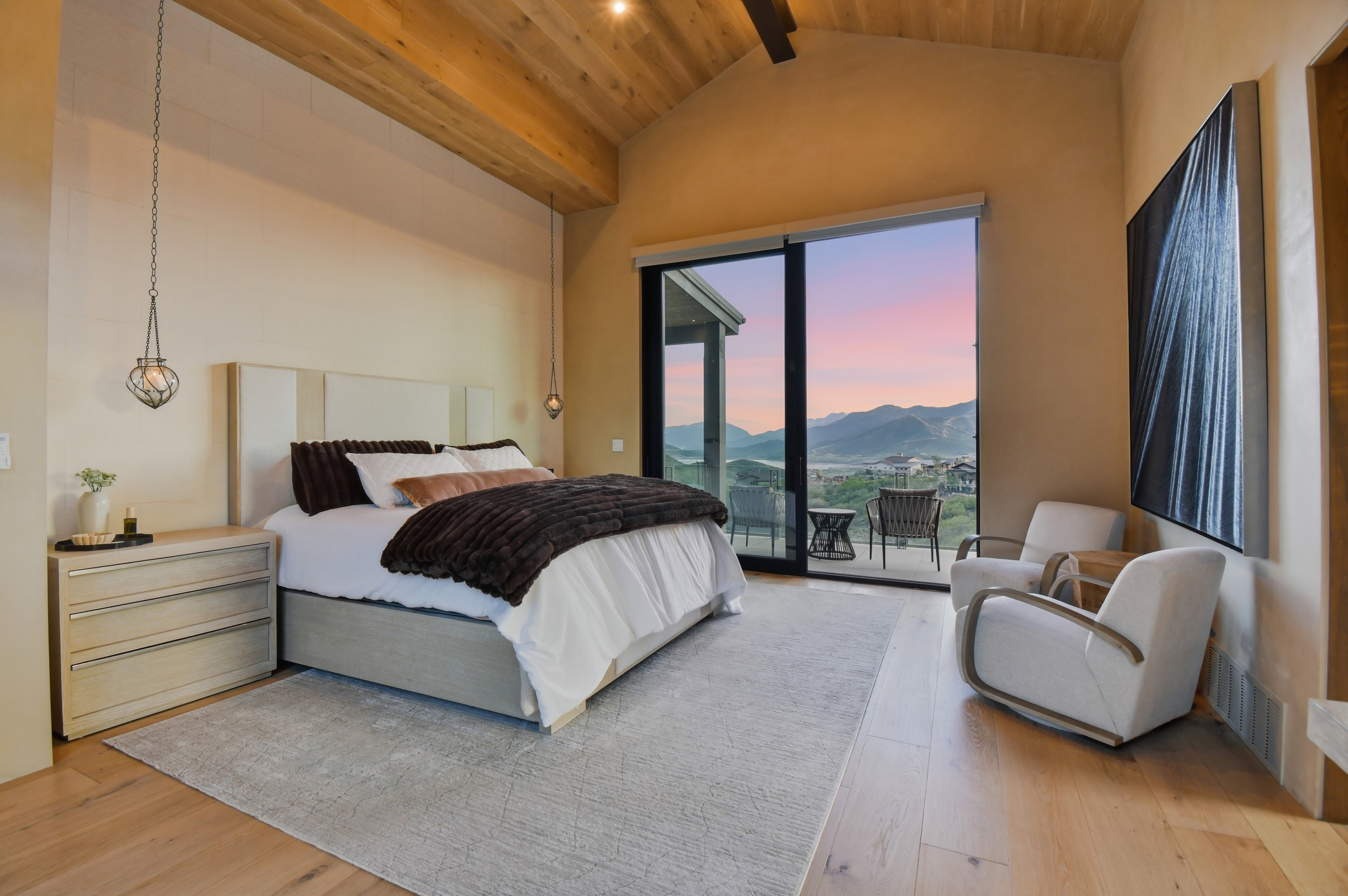 Vaulted wood-paneled ceilings with exposed beams, wood-finish flooring, a full-height sliding glass door, and recessed wall paneling