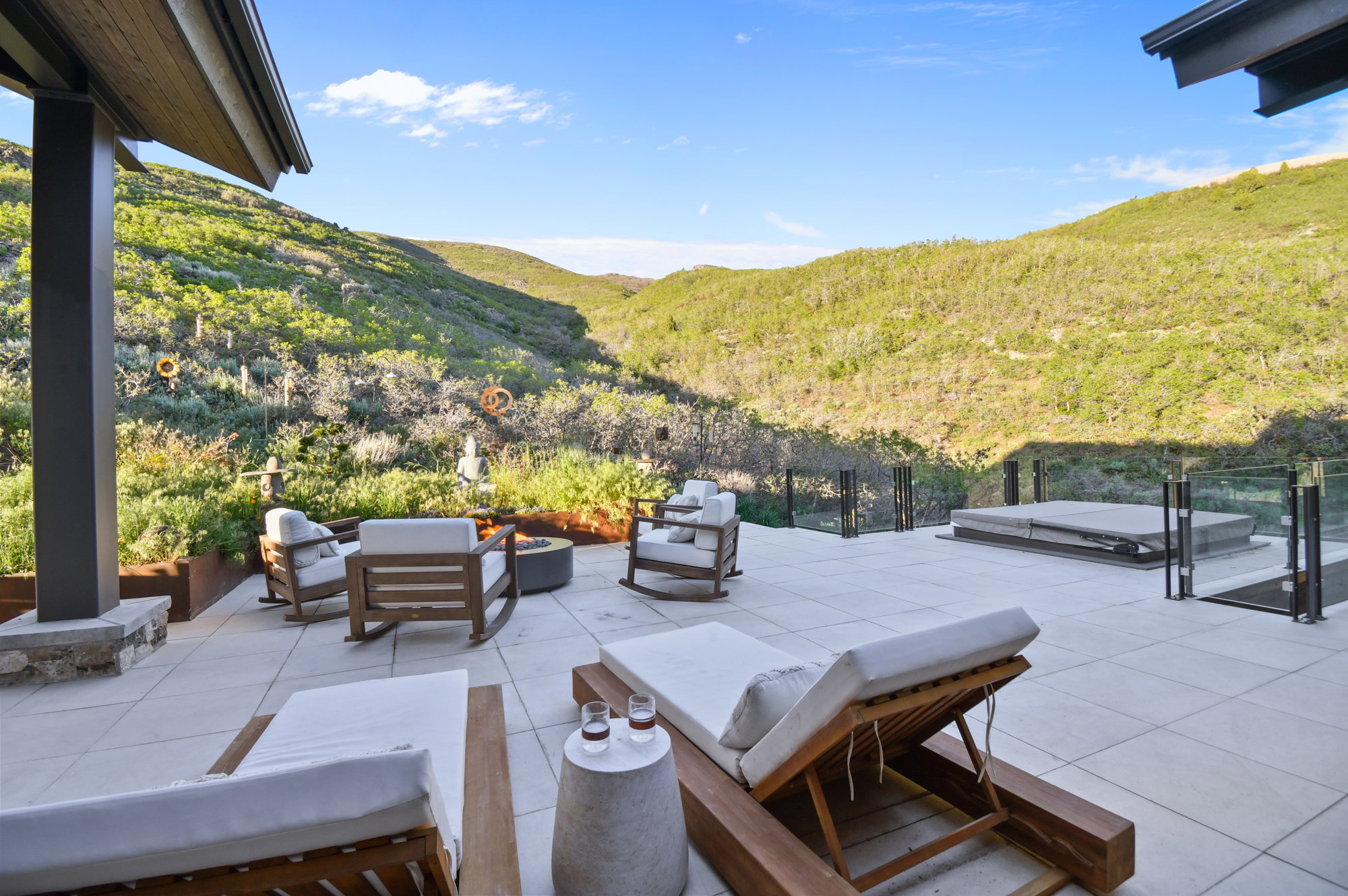 Expansive outdoor patio featuring light-toned paver flooring, a built-in fire pit, and a covered spa