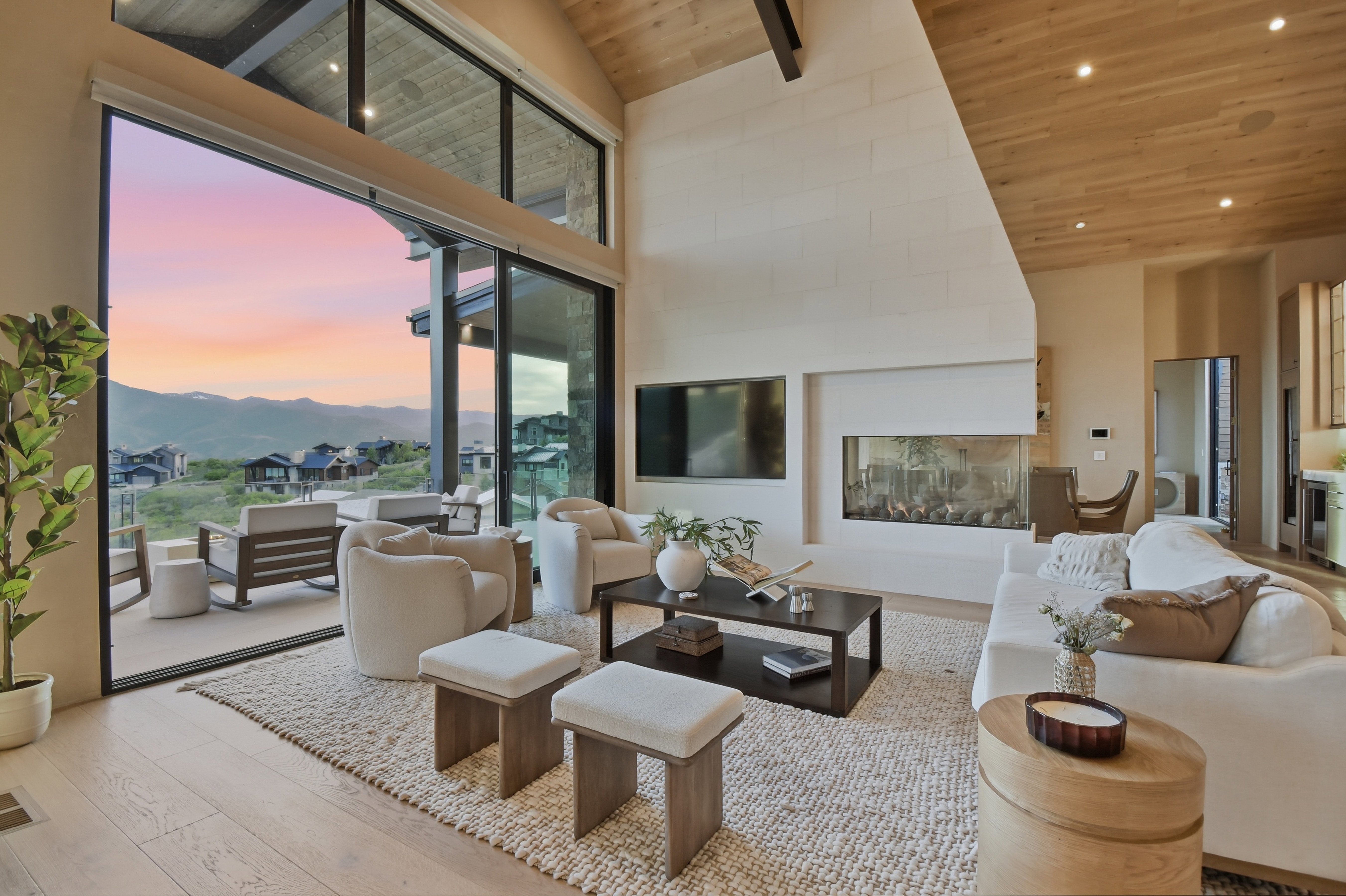 Vaulted ceiling with wood-finish planks, expansive sliding glass doors, contemporary linear fireplace, light wood-finish flooring, and recessed lighting