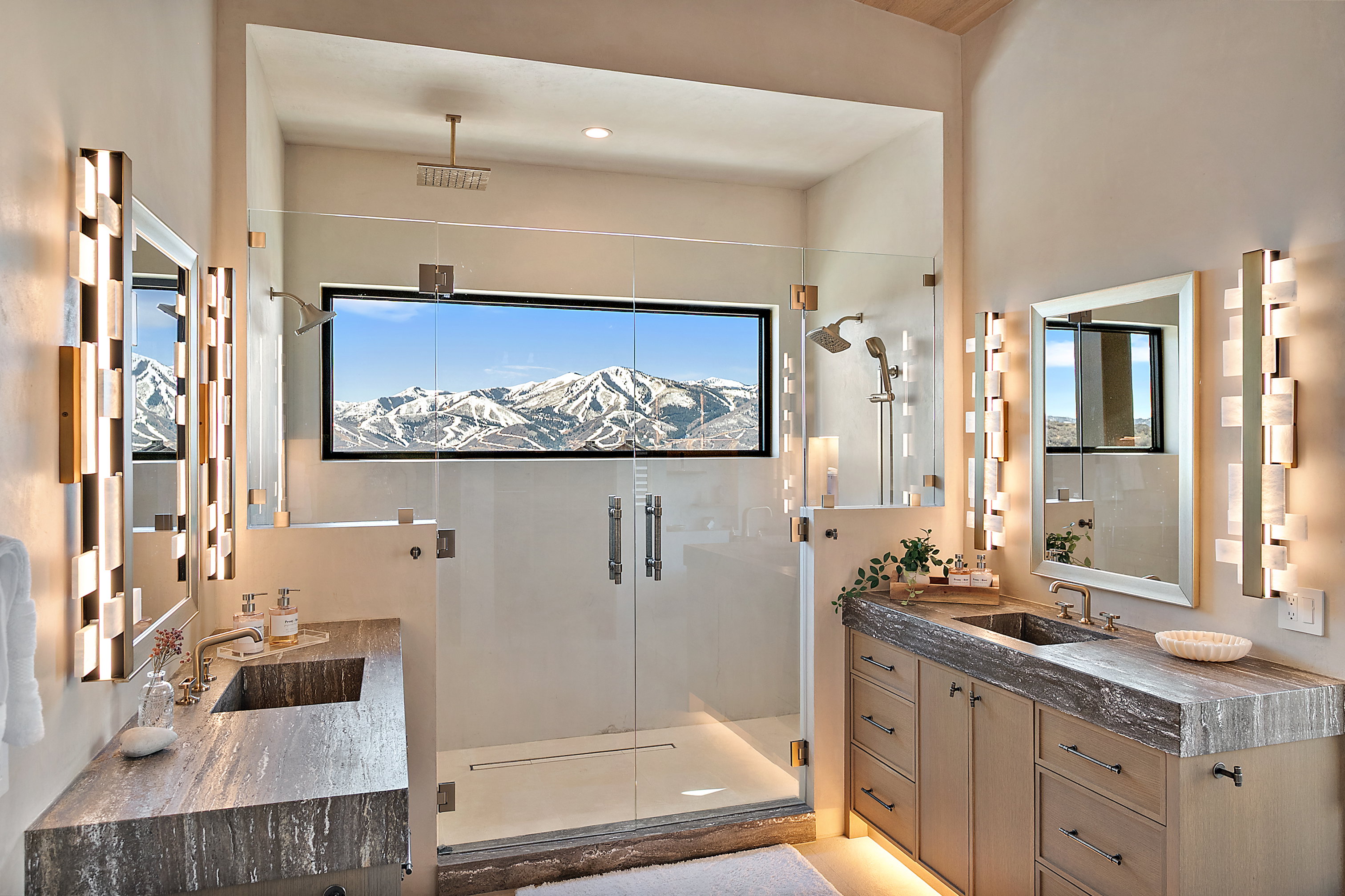 Dual vanity bathroom featuring a glass-enclosed shower with mountain scenery, dual showerheads, and a rainfall shower