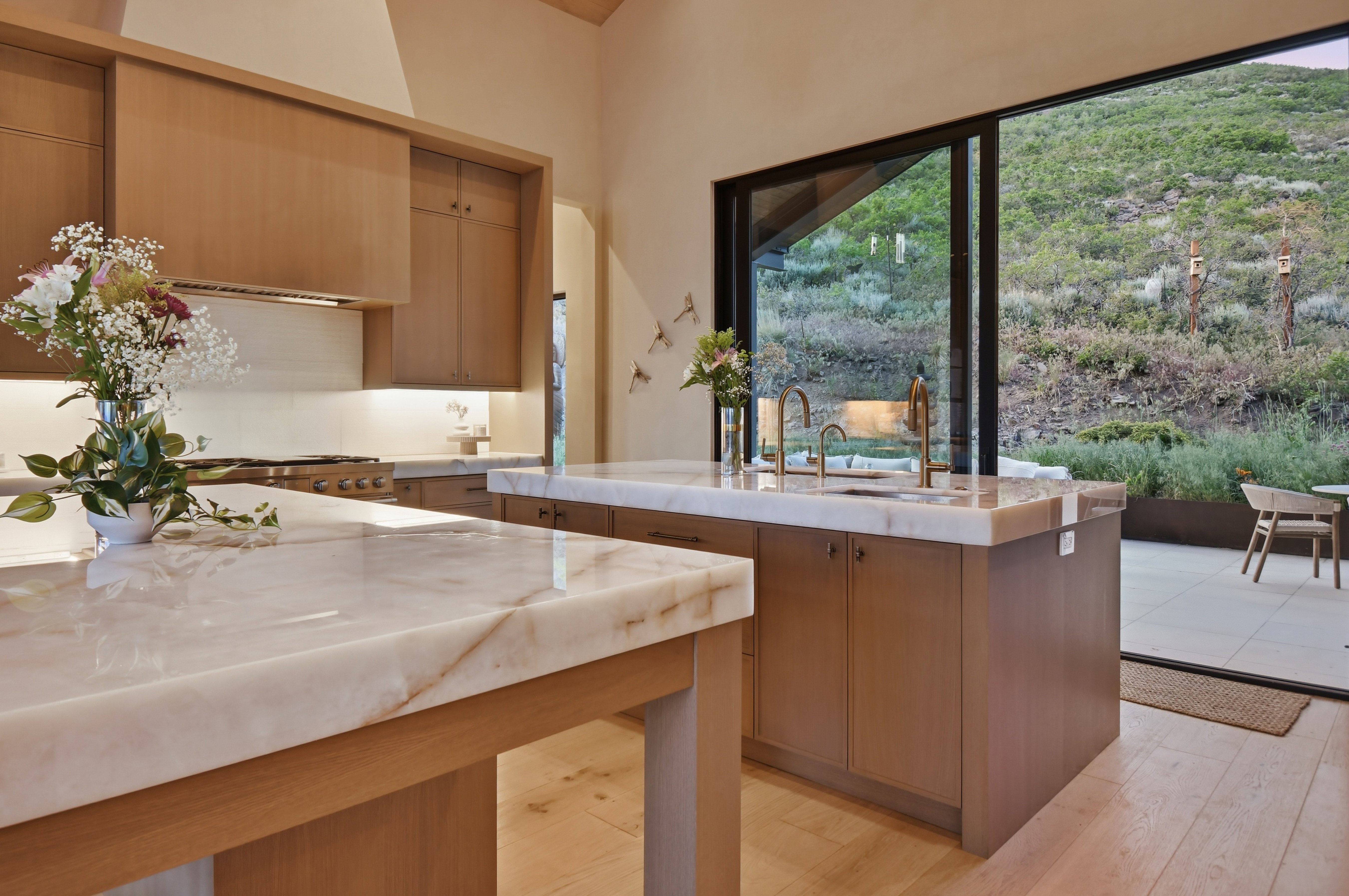 Kitchen featuring light wood-finish cabinetry, light stone countertops, integrated range, and a large sliding glass door