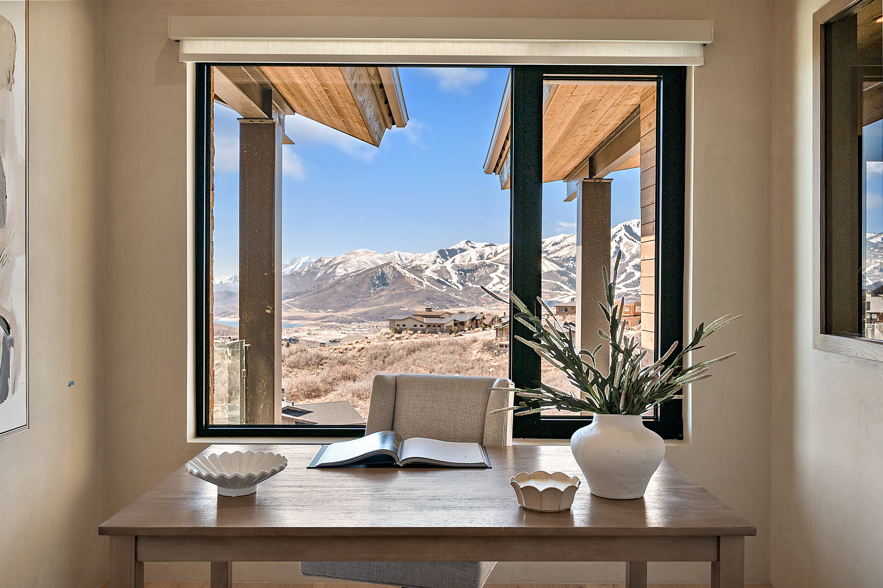 Expansive window framing snow-capped mountains and distant structures