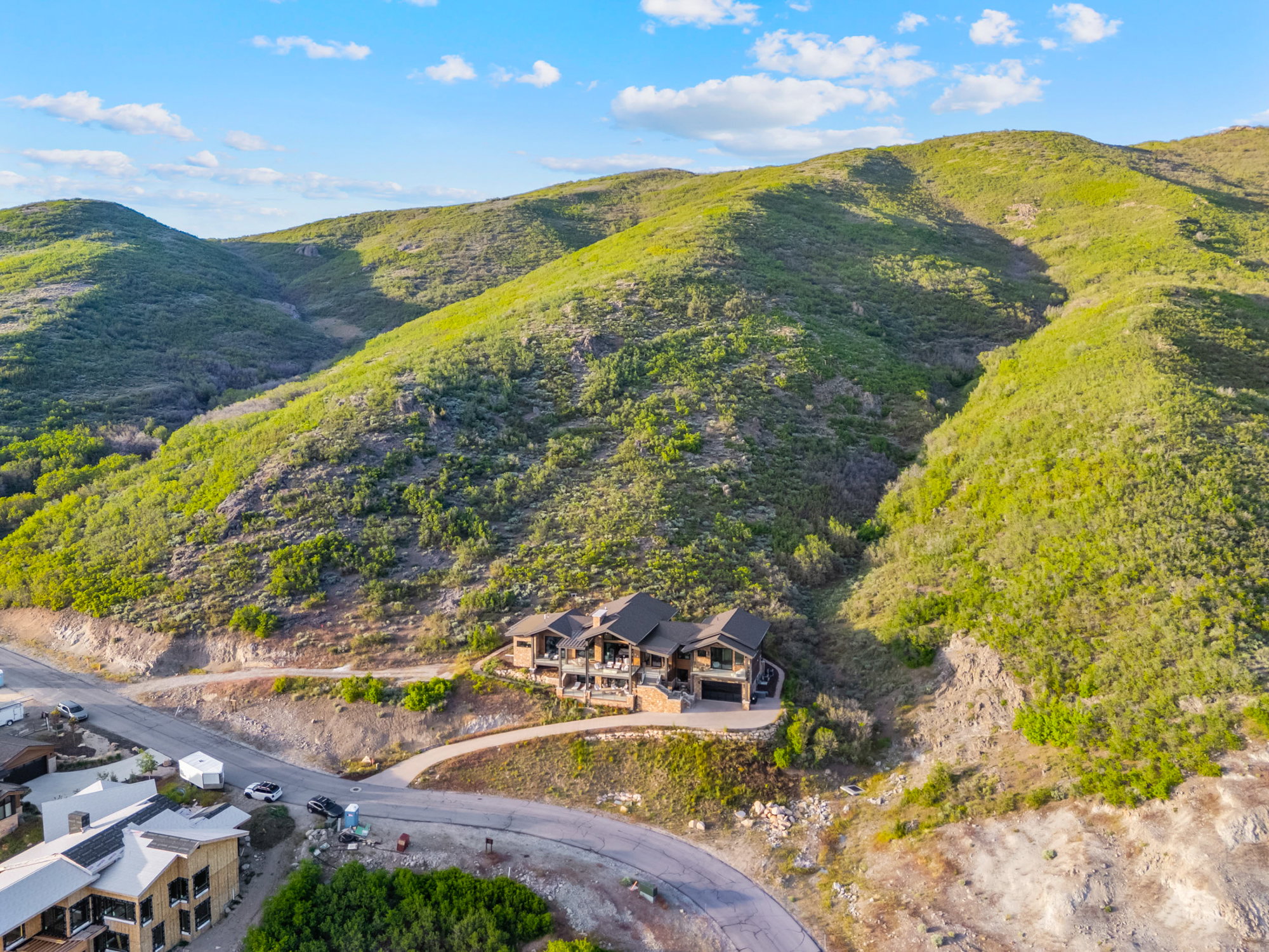Mountainous landscape featuring a contemporary multi-level residence with dark siding, prominent balconies, and an integrated garage