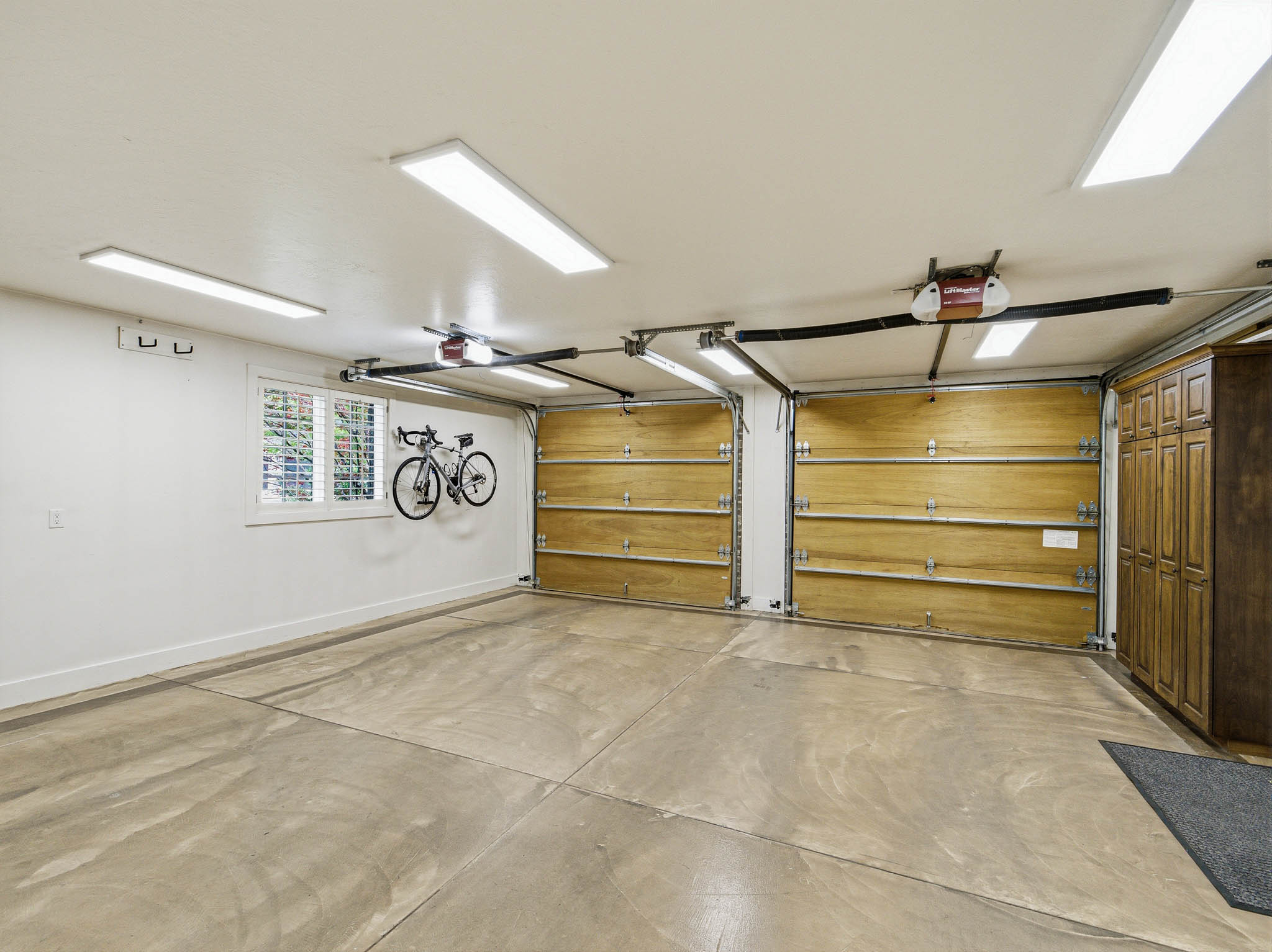 Two-car garage featuring a concrete floor, two wood-paneled garage doors, and built-in wood cabinetry