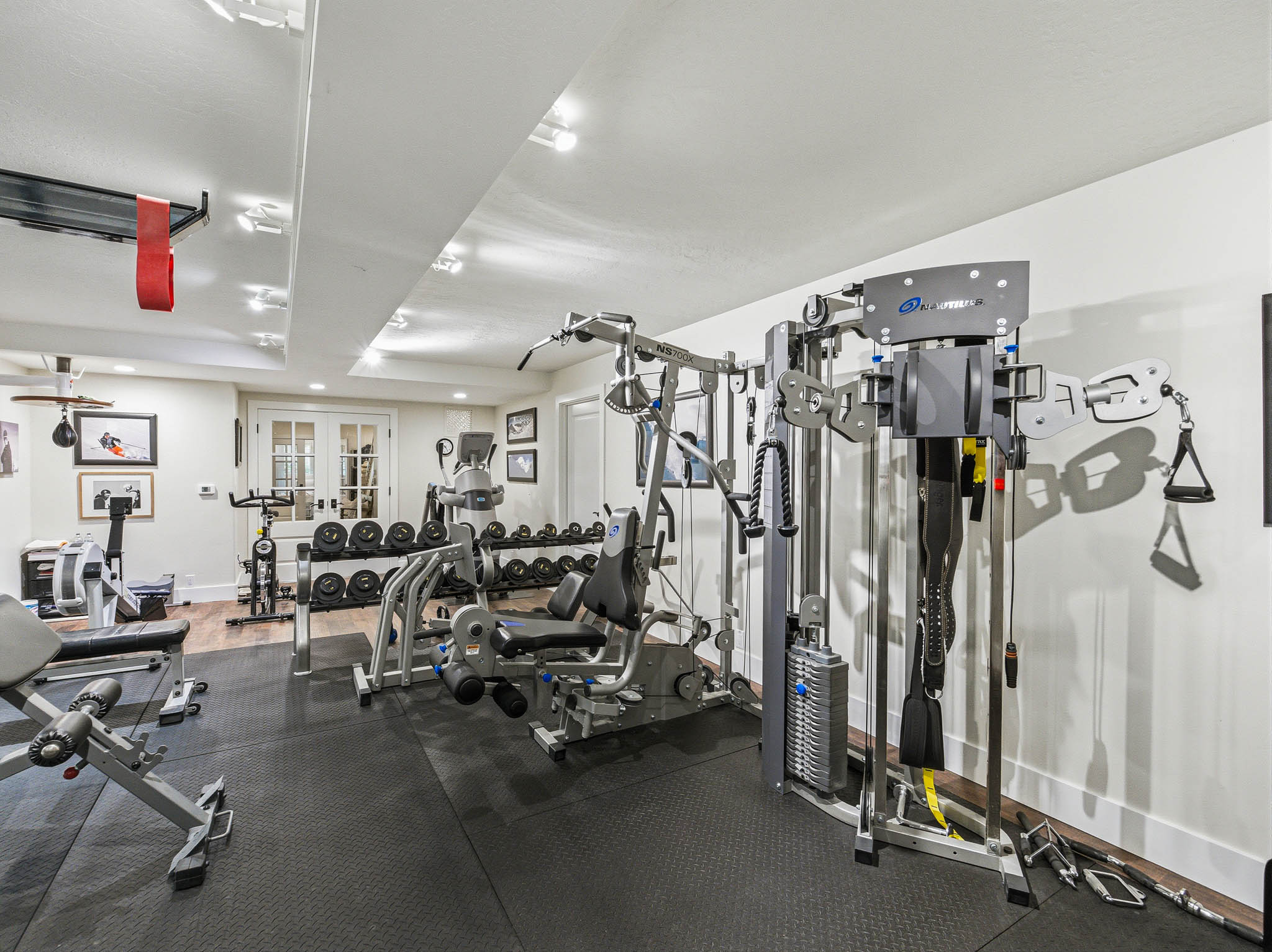 Dedicated fitness space featuring rubberized flooring, recessed lighting, white walls, and French doors with glass panels
