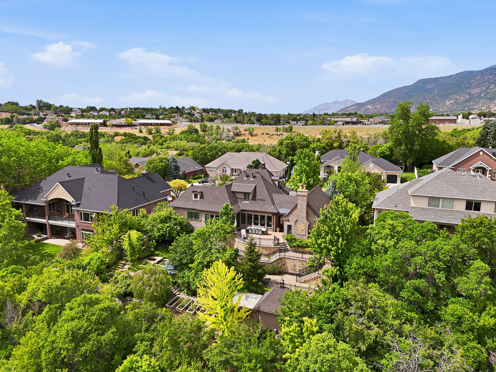 Expansive property featuring a multi-level home with a dark shingle roof and brick exterior
