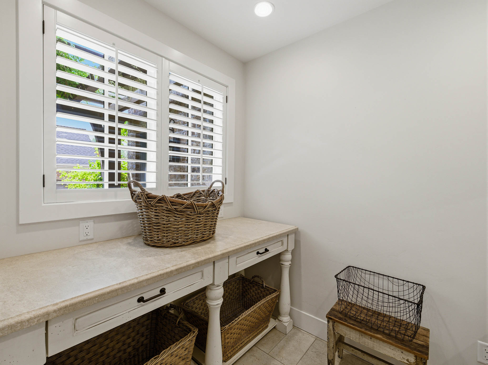 Bright interior space featuring a window with white plantation shutters, a recessed ceiling light, and light-toned tile flooring