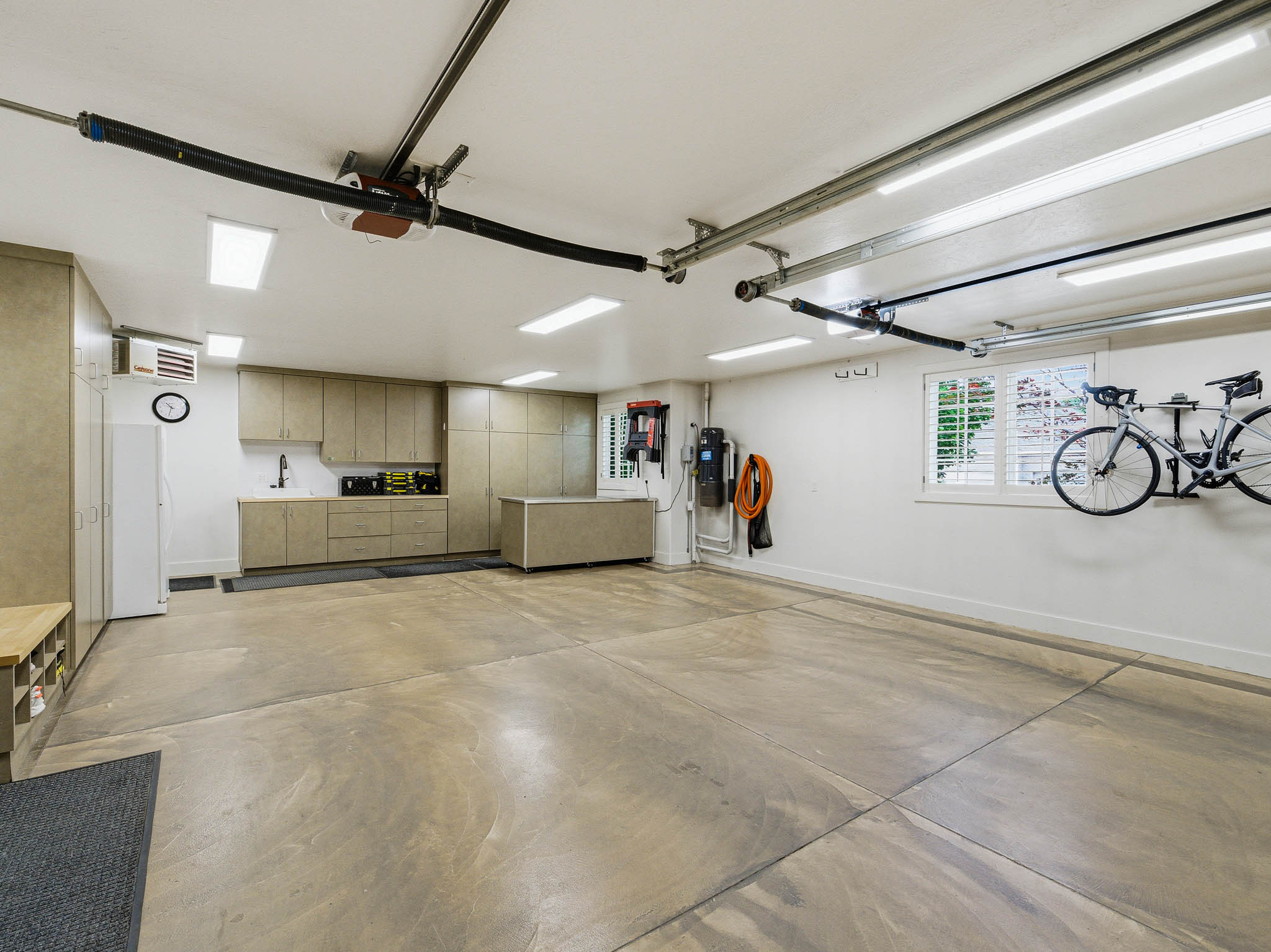 Spacious garage featuring extensive built-in cabinetry, an integrated sink with a countertop, recessed lighting, and a finished concrete floor