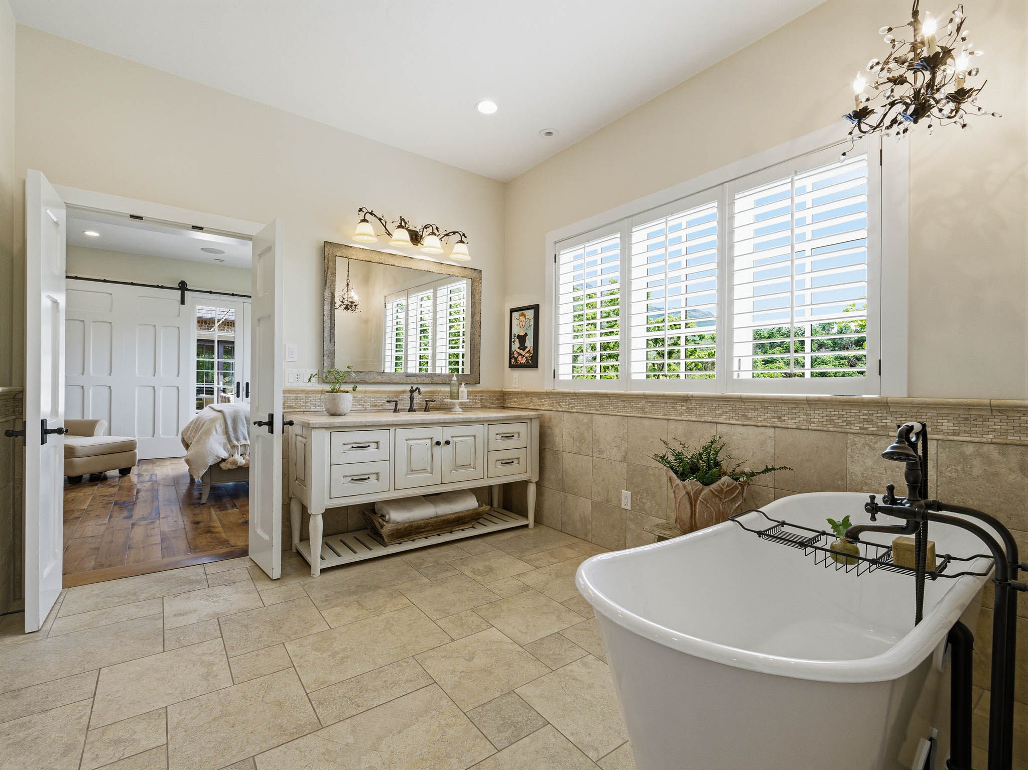 Spacious bathroom featuring a freestanding soaking tub, a large vanity with dual sinks, and extensive tile flooring