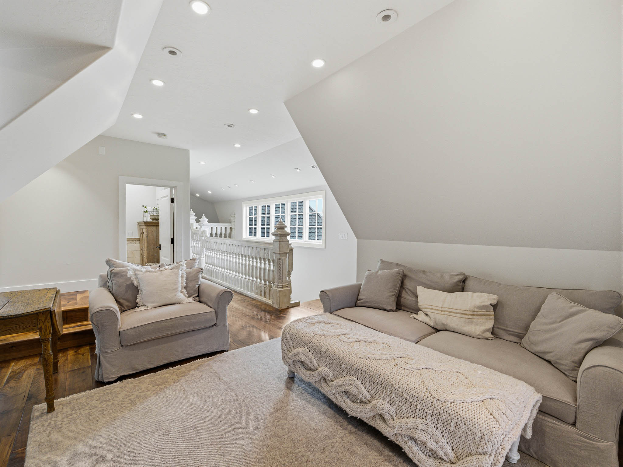 Upper-level landing featuring vaulted ceilings, recessed lighting, and rich wood-finish flooring