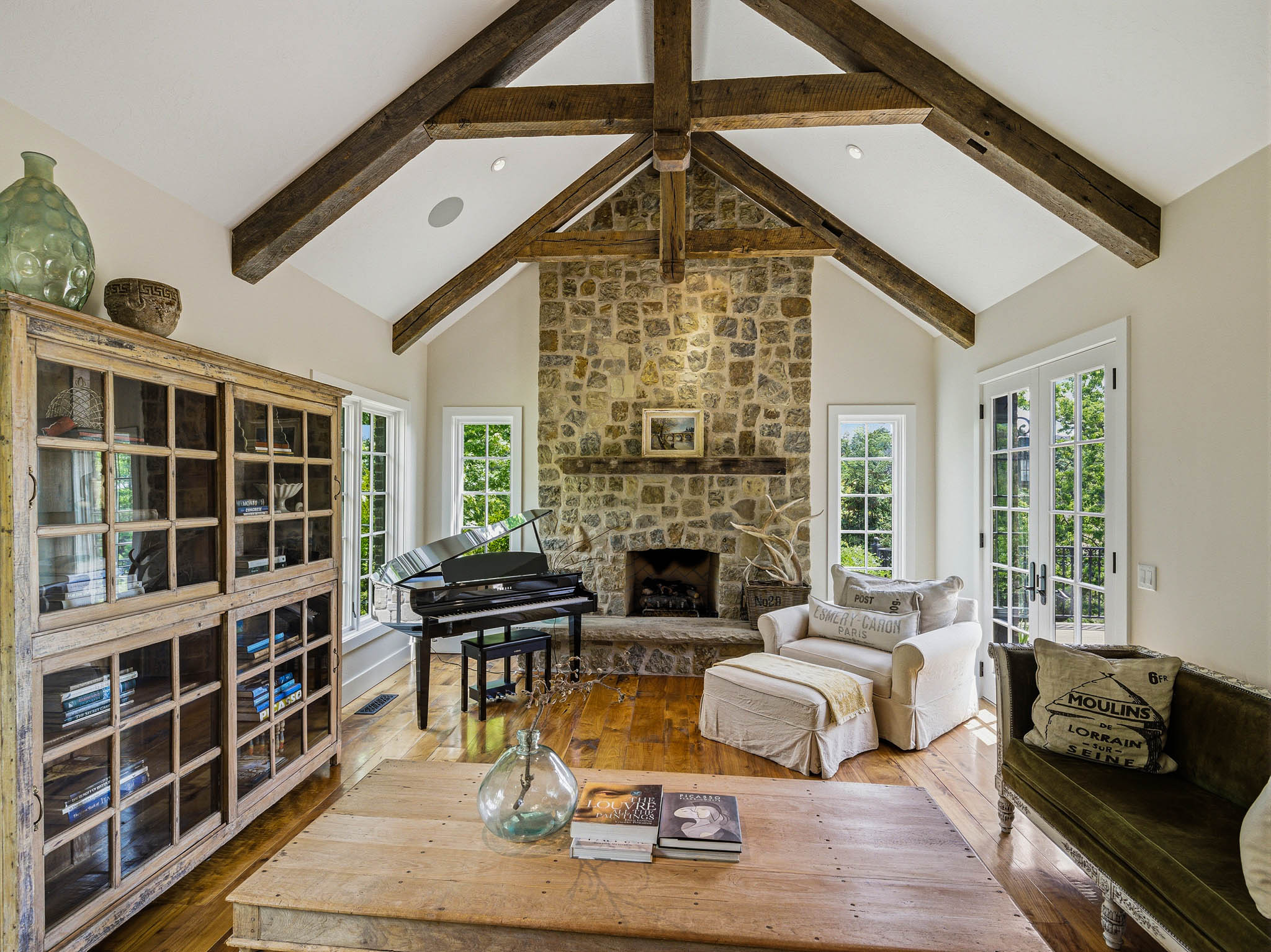 Spacious living area featuring exposed wood beams, a stone fireplace, wood-finish flooring, recessed lighting, and French doors