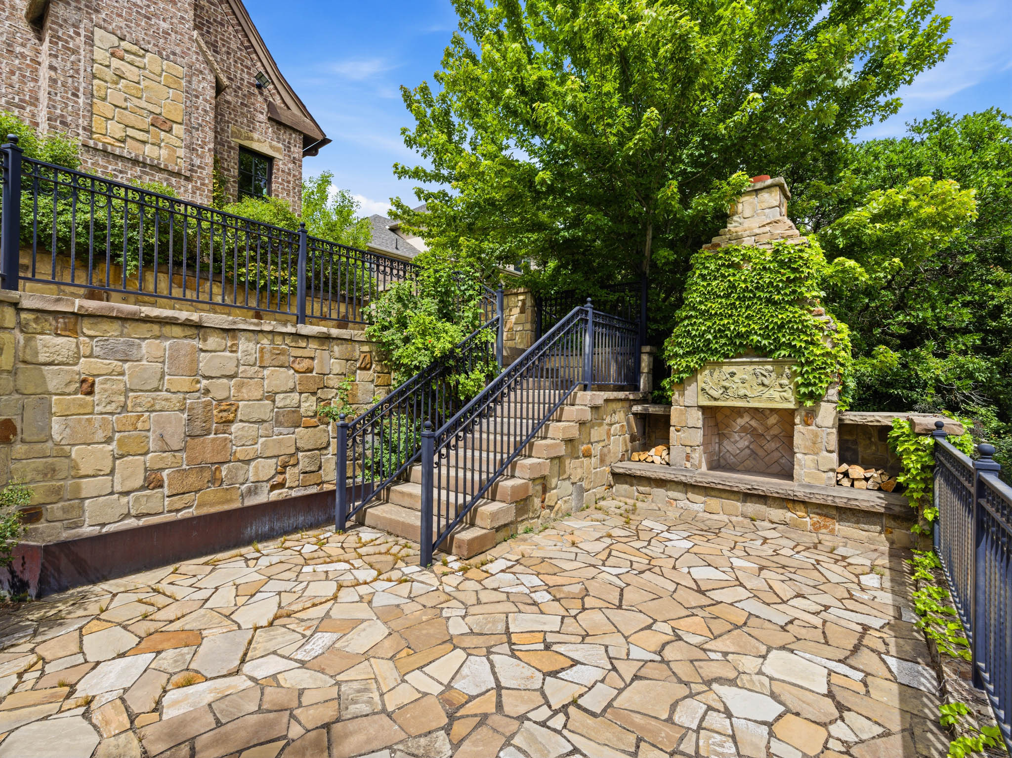 Expansive flagstone patio featuring a built-in stone fireplace with decorative carving and integrated wood storage