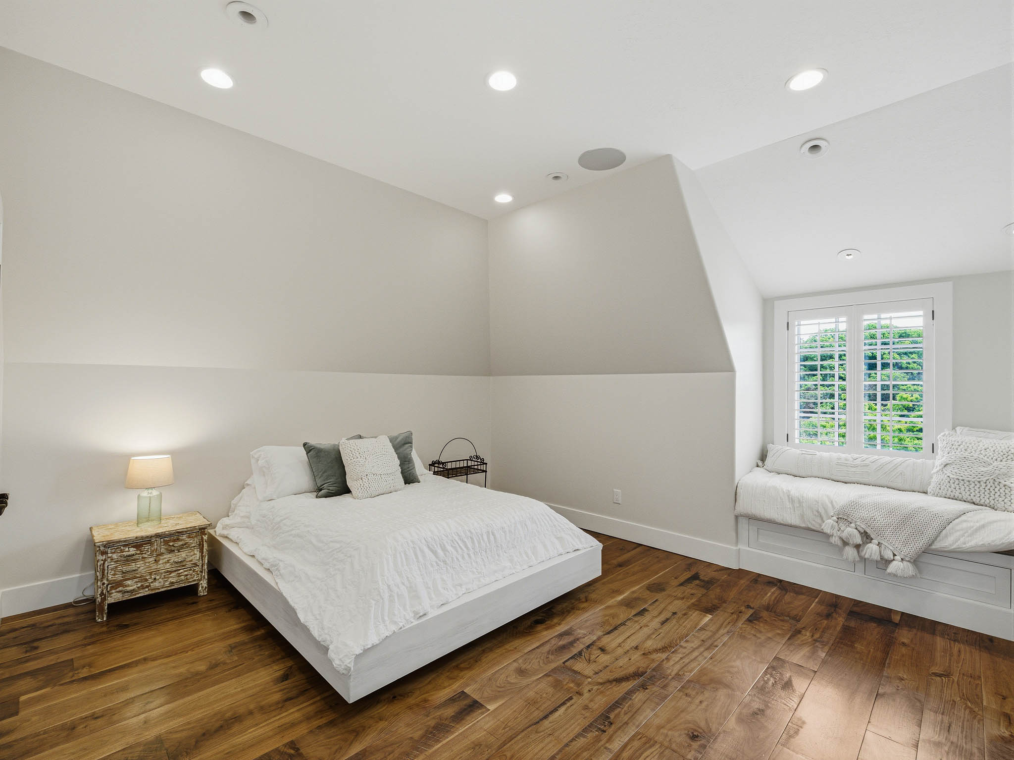 Spacious room featuring wood-finish flooring, a built-in window seat, recessed lighting, and a window with white shutters