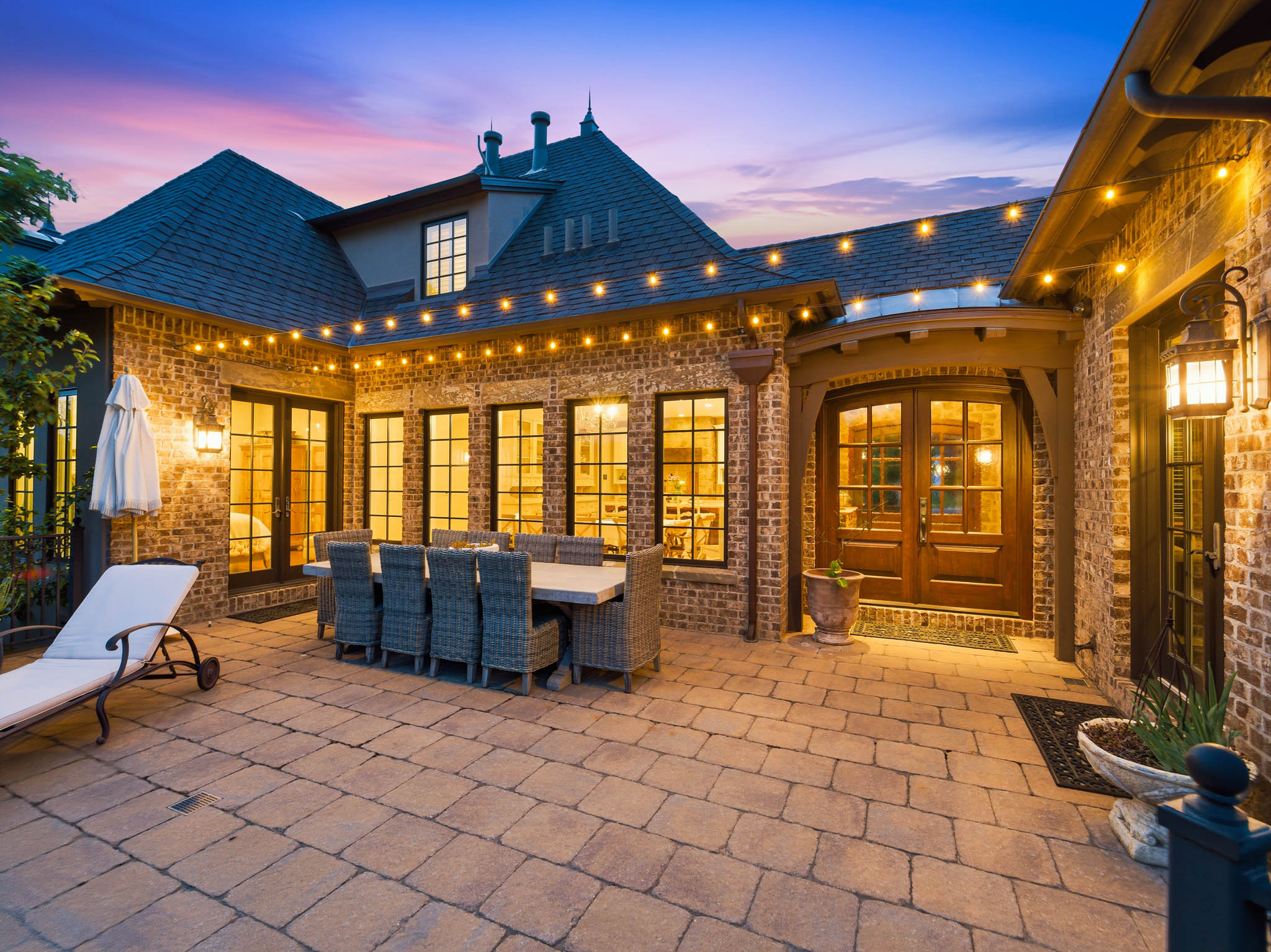 Extensive paver patio featuring brick exterior architecture and multiple French-style doors