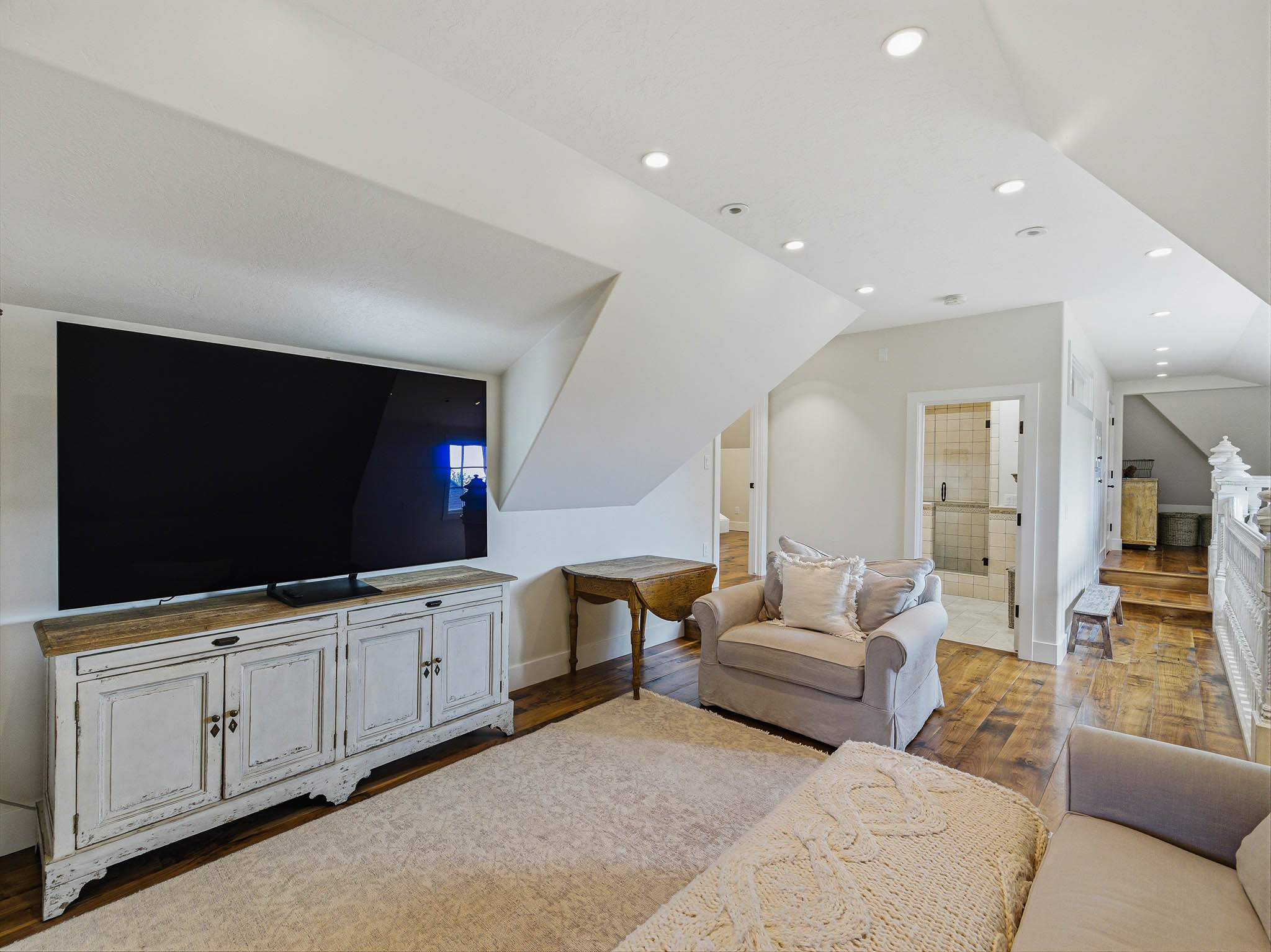 Finished upper-level space featuring recessed lighting, wood-finish flooring, and a white distressed-look media console