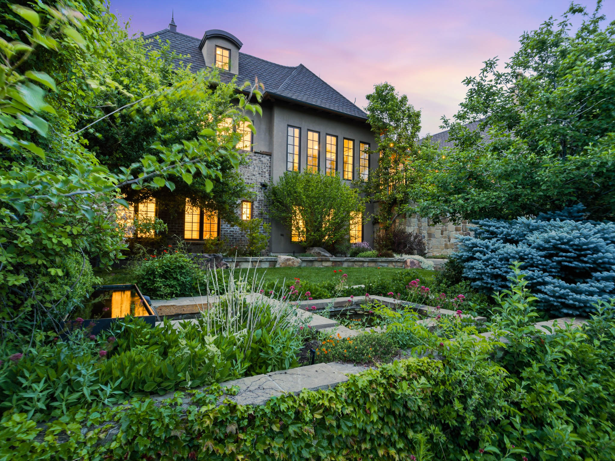 Landscaped terraced garden featuring lush plantings, a multi-level water feature, and stone retaining walls