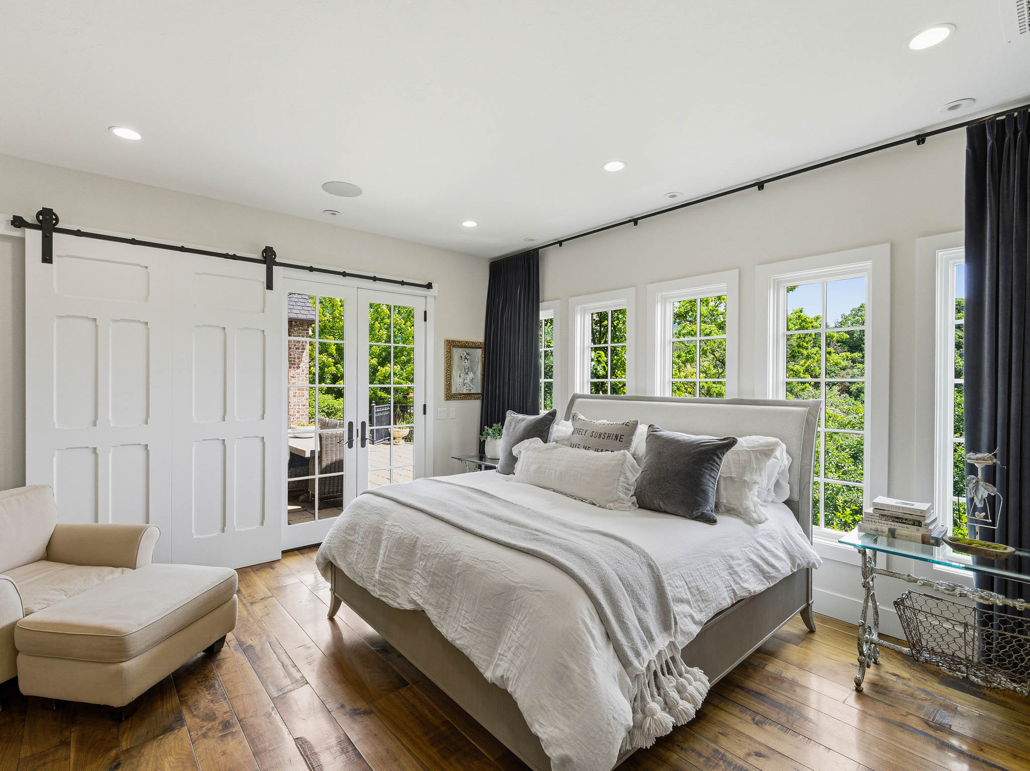 Hardwood flooring throughout, featuring a wall of multiple windows, recessed lighting, and a barn door entry to an outdoor space