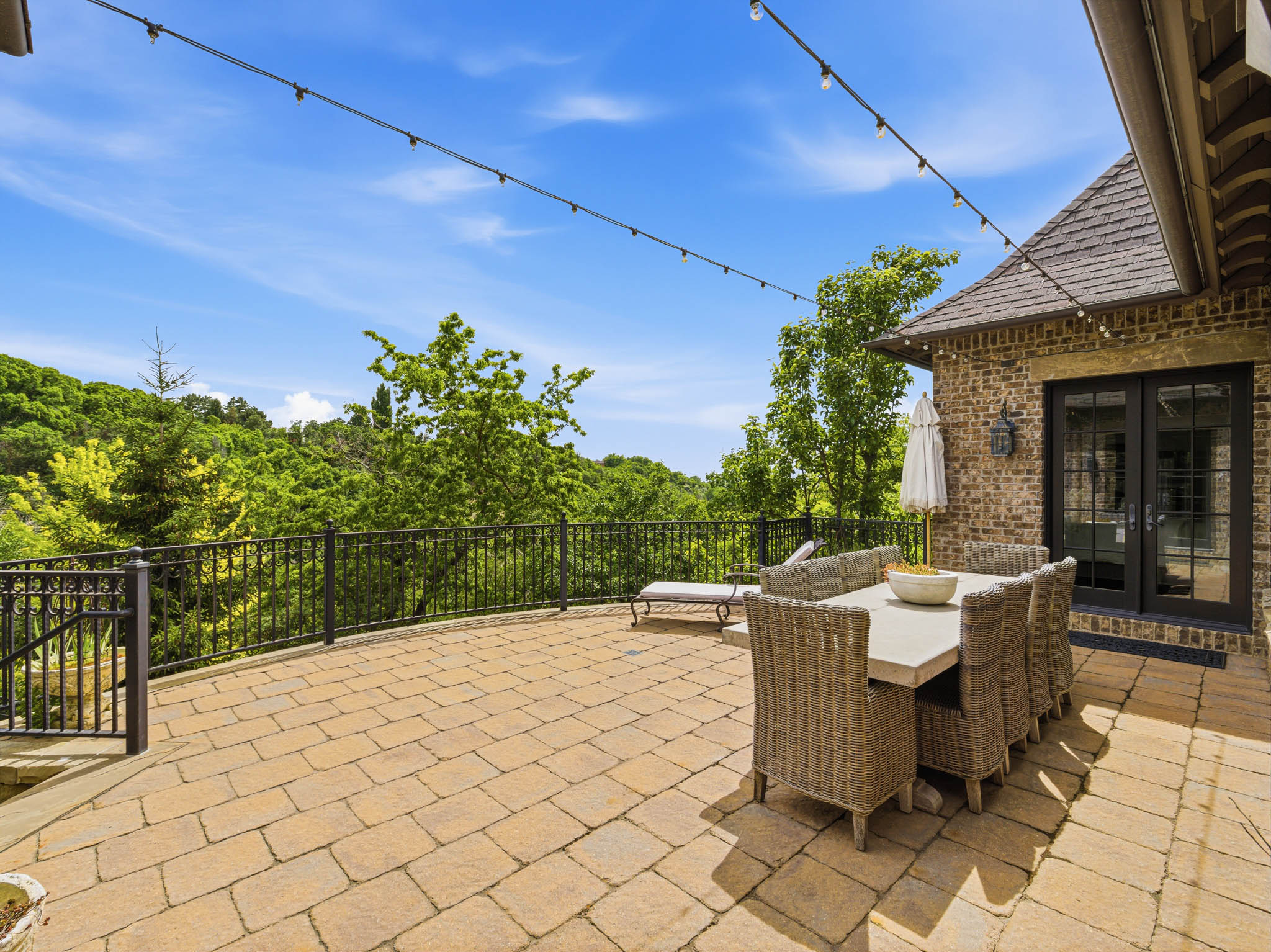 Expansive paver patio with a black iron railing