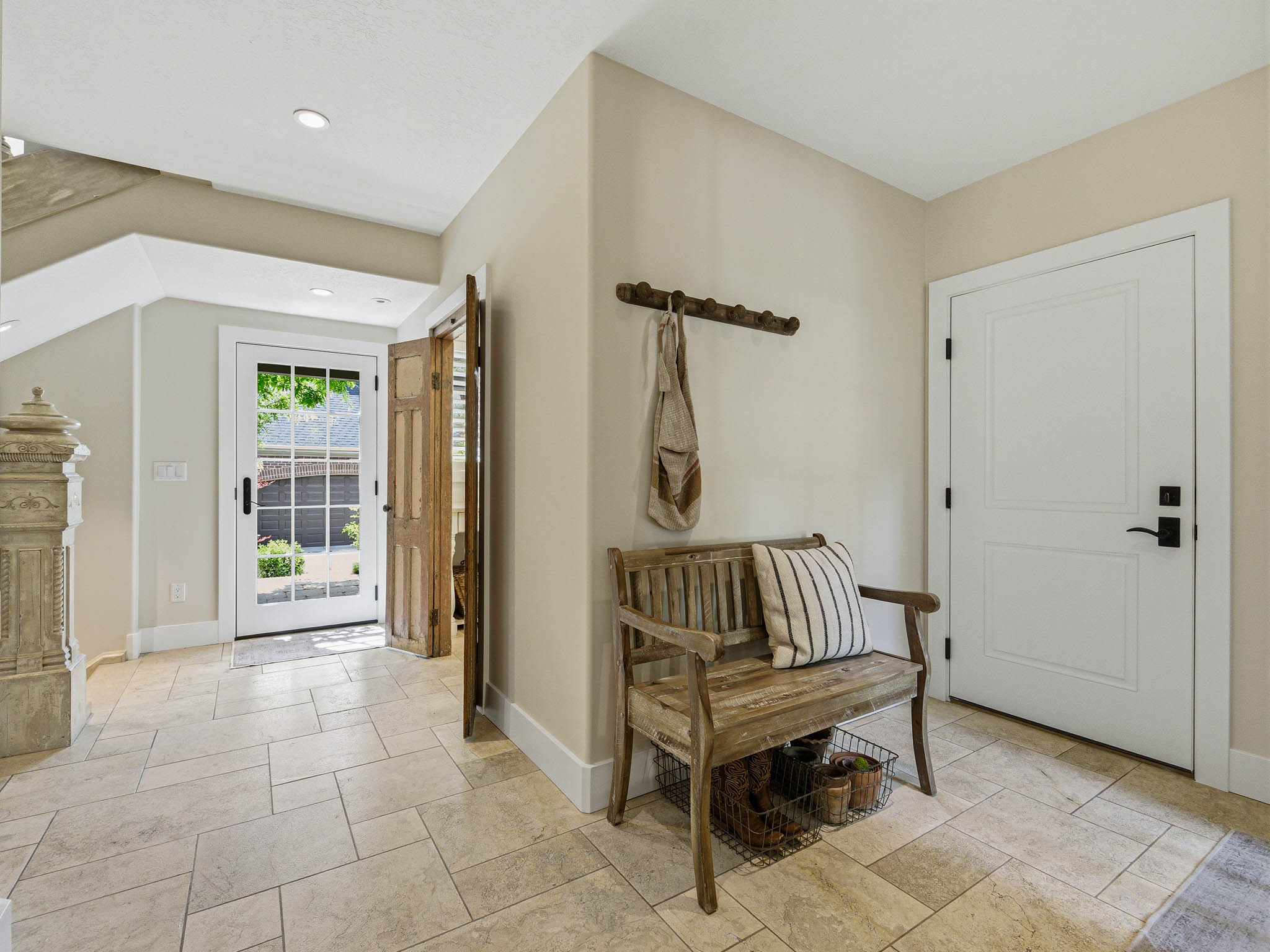 Entryway featuring light-toned tile flooring, recessed lighting, a paneled white door with black hardware, a glass-paned exterior door, and a carved newel post