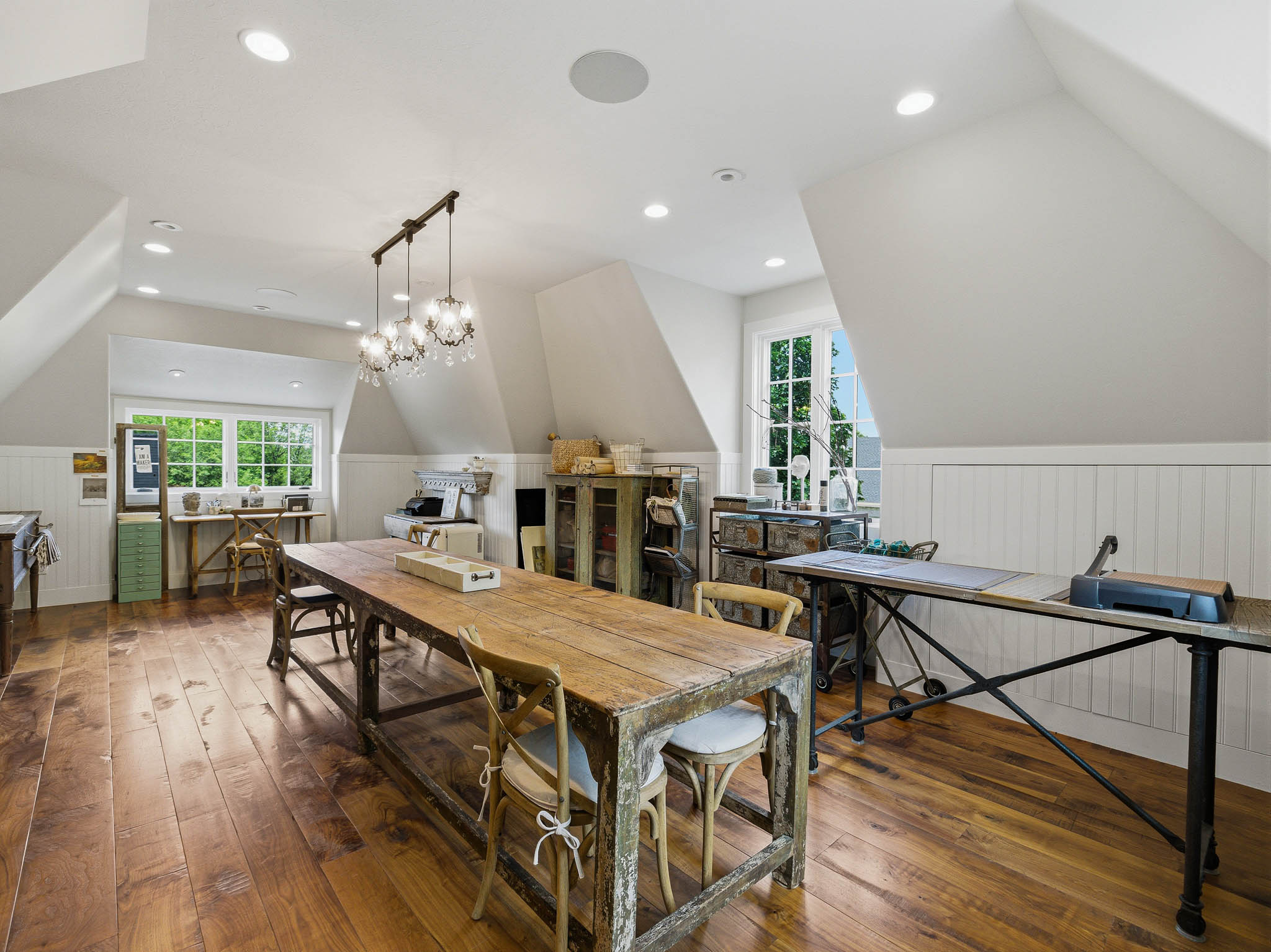 Spacious room featuring rich wood-finish flooring, white wainscoting, and recessed lighting