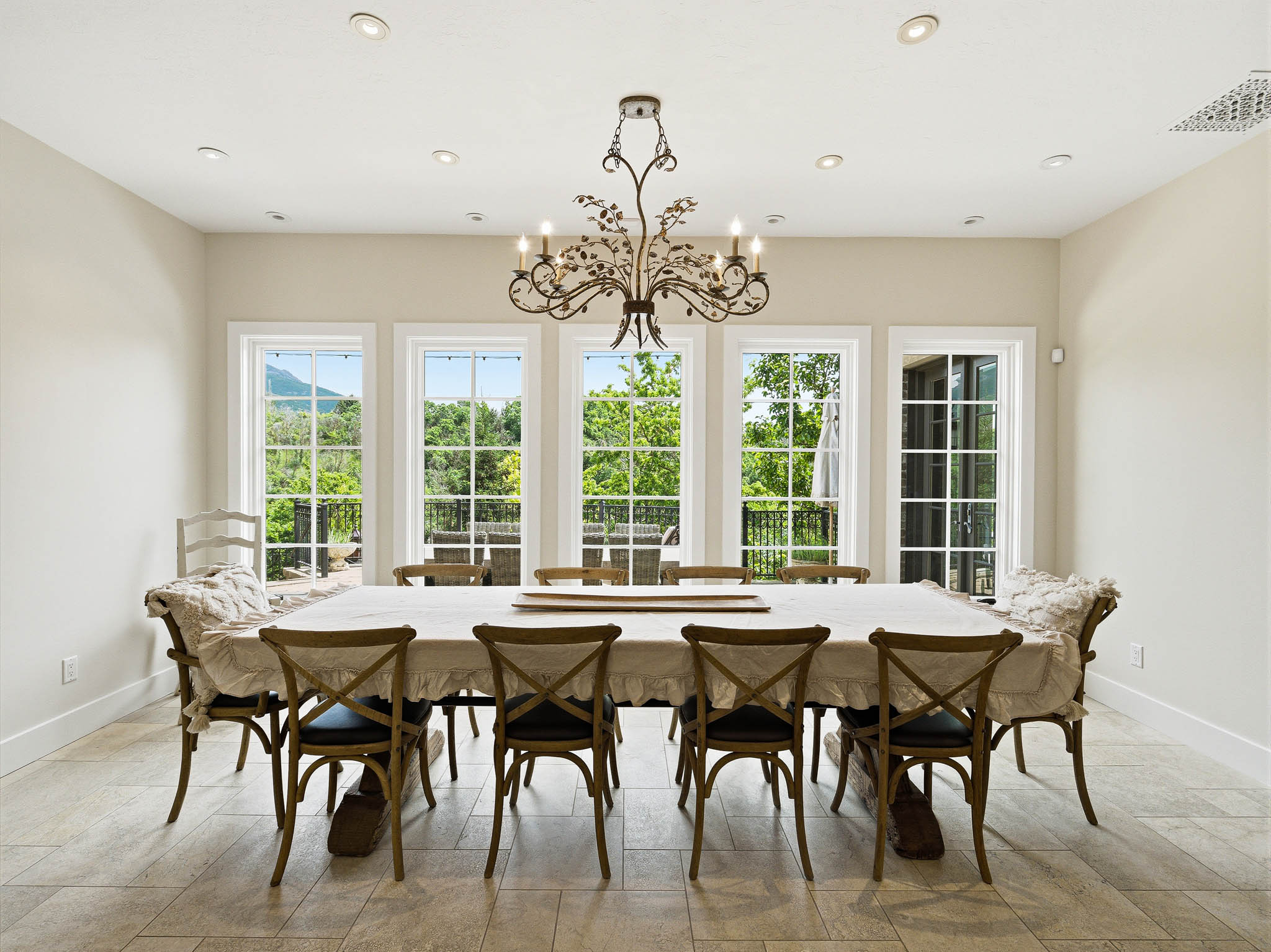 Spacious dining area featuring a prominent chandelier, recessed lighting, and large windows