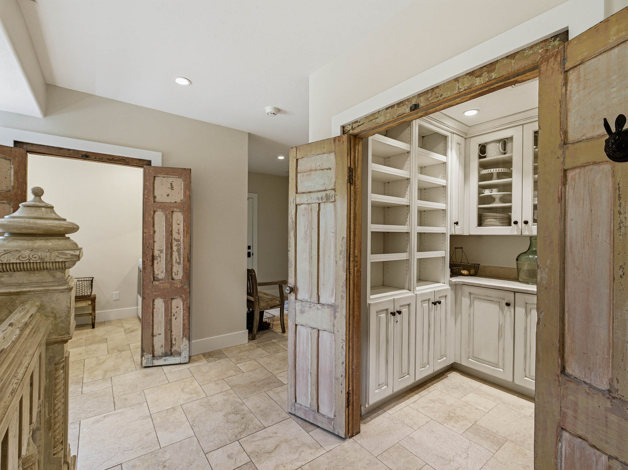 Custom distressed wood sliding barn doors open to an interior space featuring extensive white built-in cabinetry