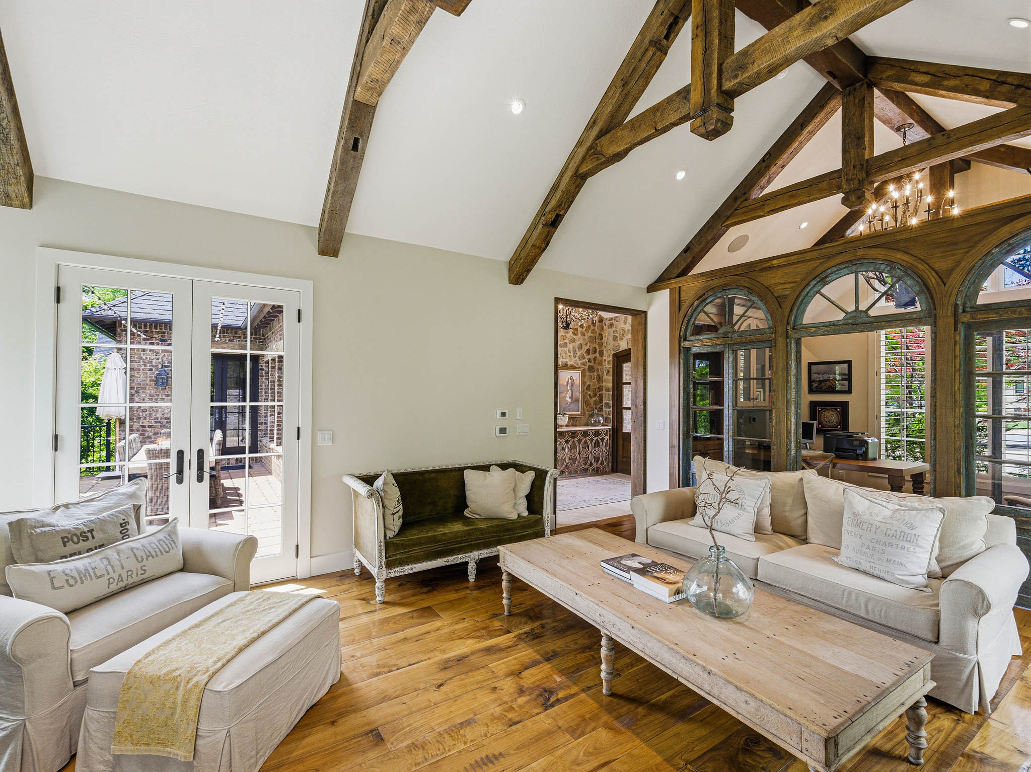 Living area featuring vaulted ceilings with exposed wood beams, wide plank wood-finish flooring, and French doors leading to an outdoor space