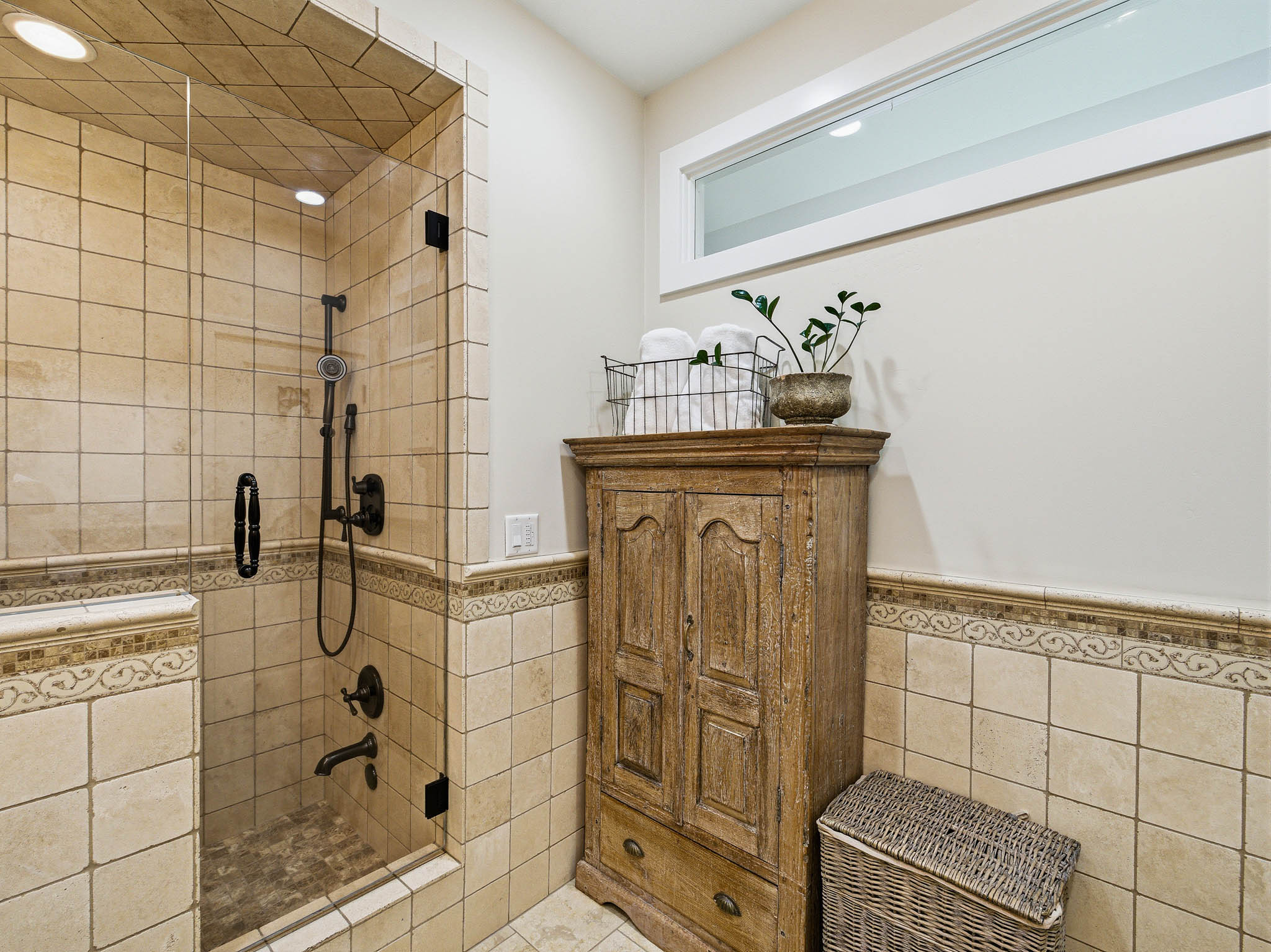 Glass-enclosed shower with a handheld showerhead and built-in niche