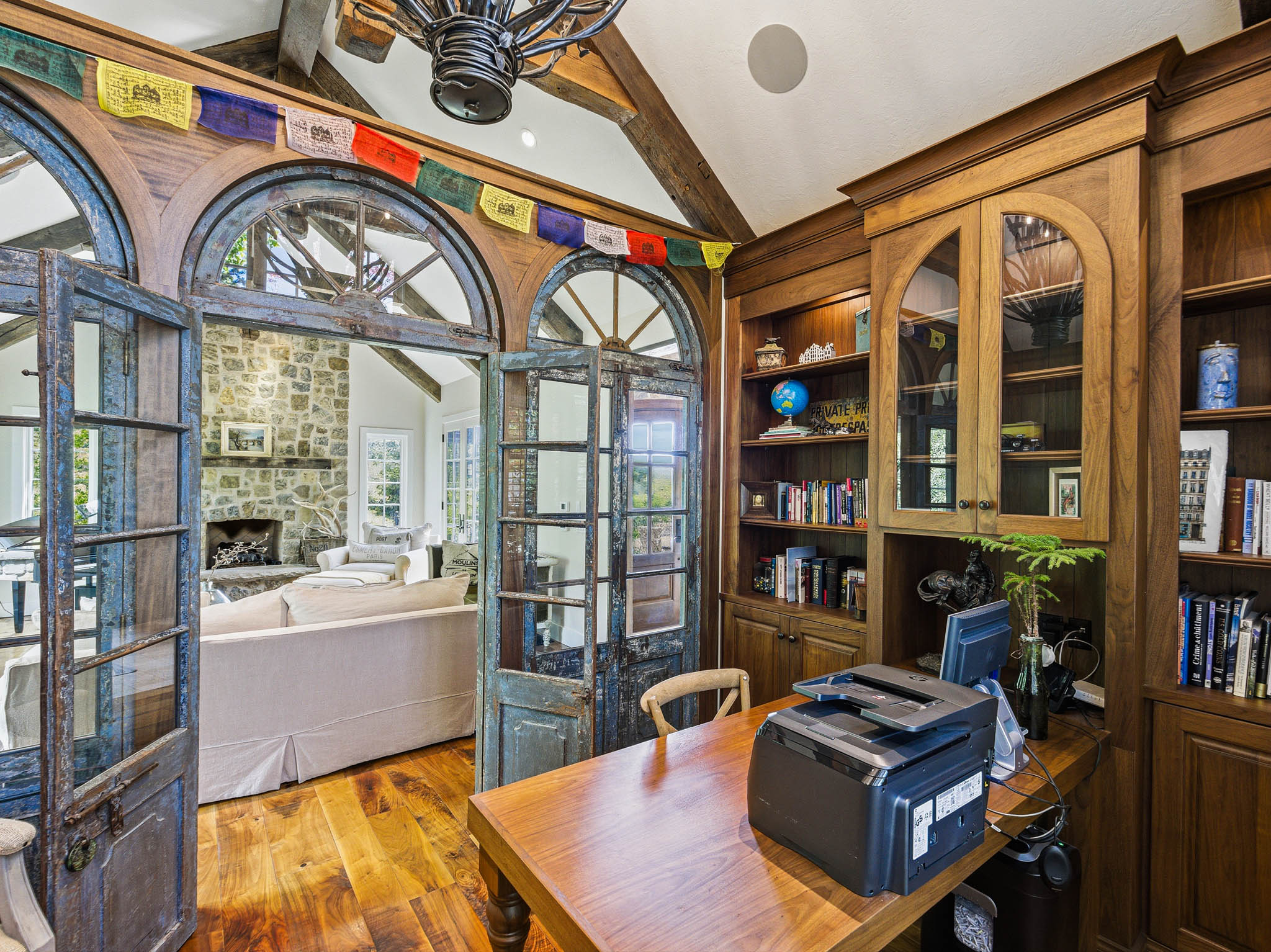 Wood-finish flooring with built-in wood cabinetry, integrated desk, and arched glass-paneled doors
