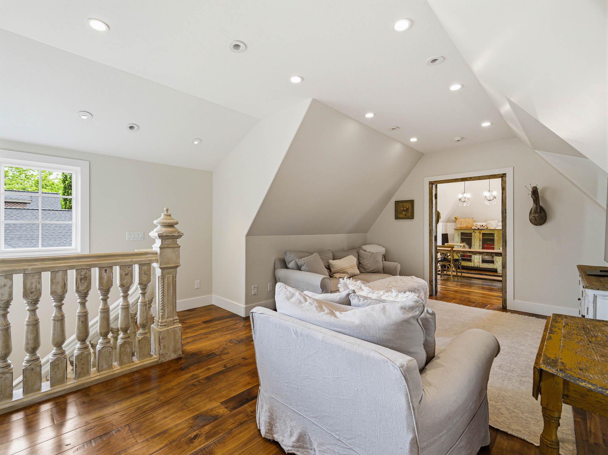 Spacious loft area featuring wood-finish flooring, recessed lighting, and a window providing natural light