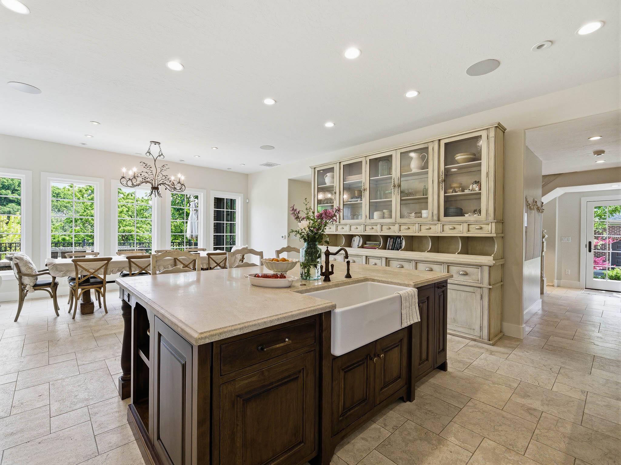 Spacious kitchen island featuring a farmhouse sink, dark wood-finish cabinetry, and a light-toned countertop