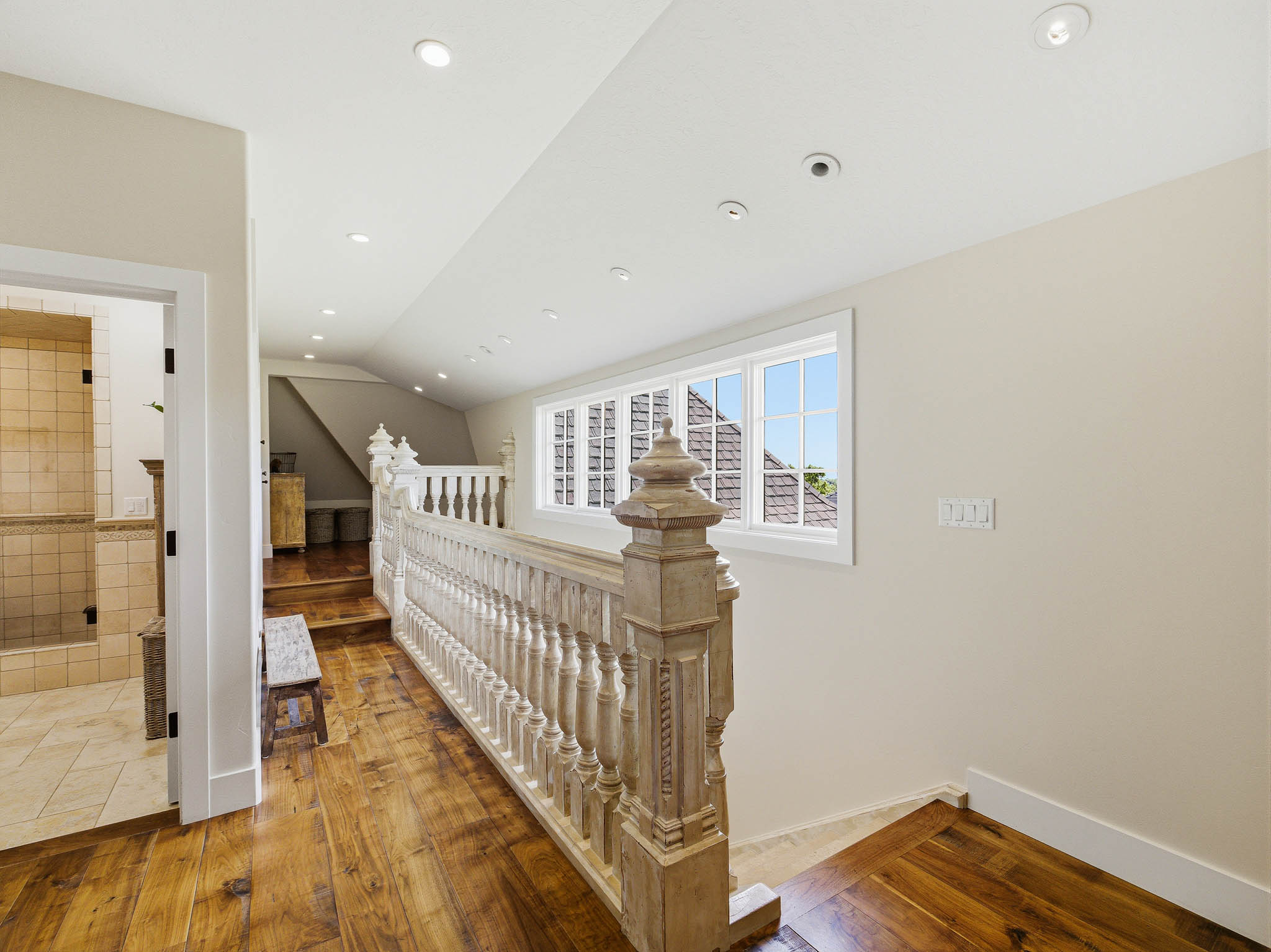 Hardwood flooring throughout the upper level hallway, featuring a carved balustrade, recessed lighting, and multipane windows