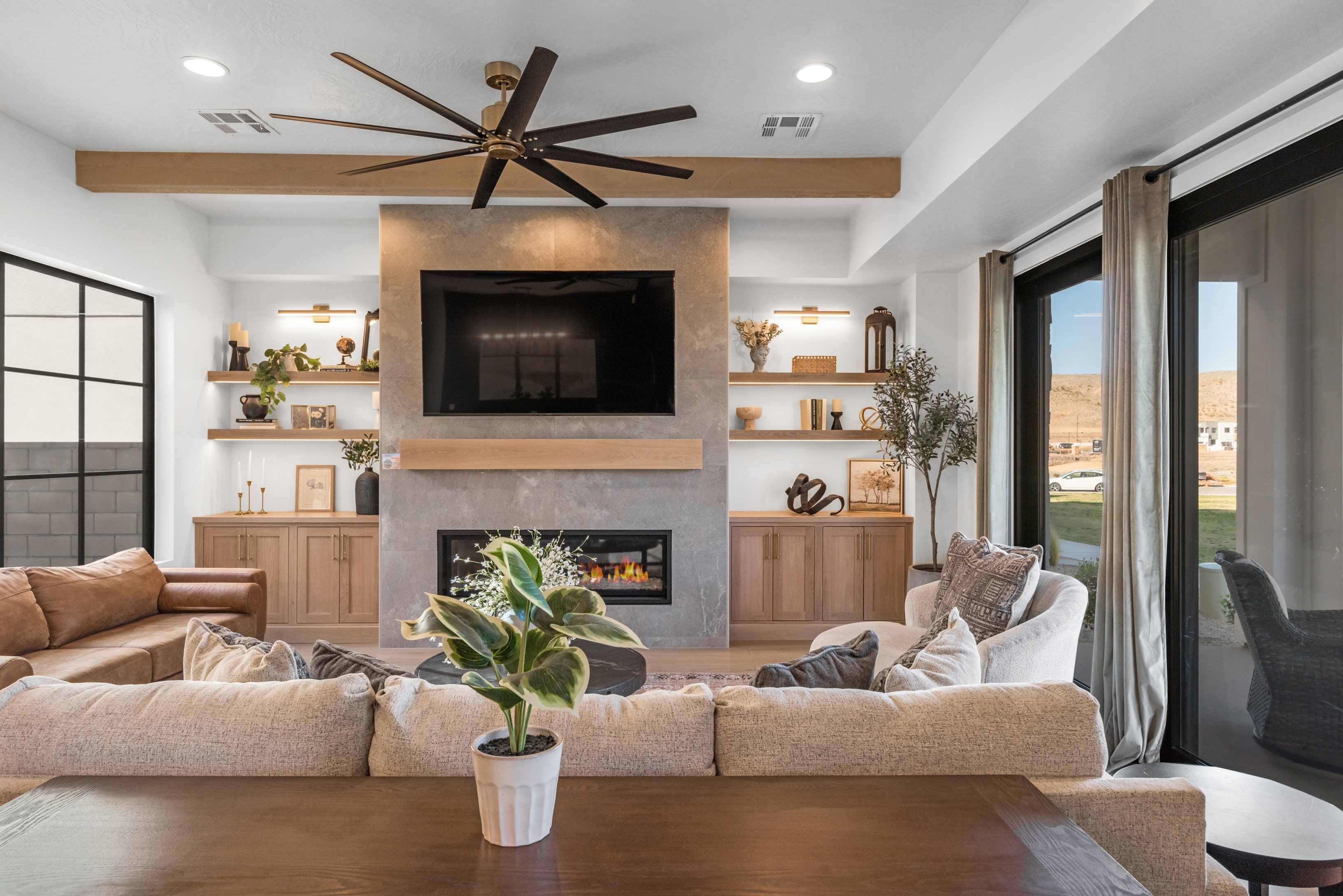 Living space featuring a stone-clad fireplace, integrated media center, recessed lighting, and a large ceiling fan
