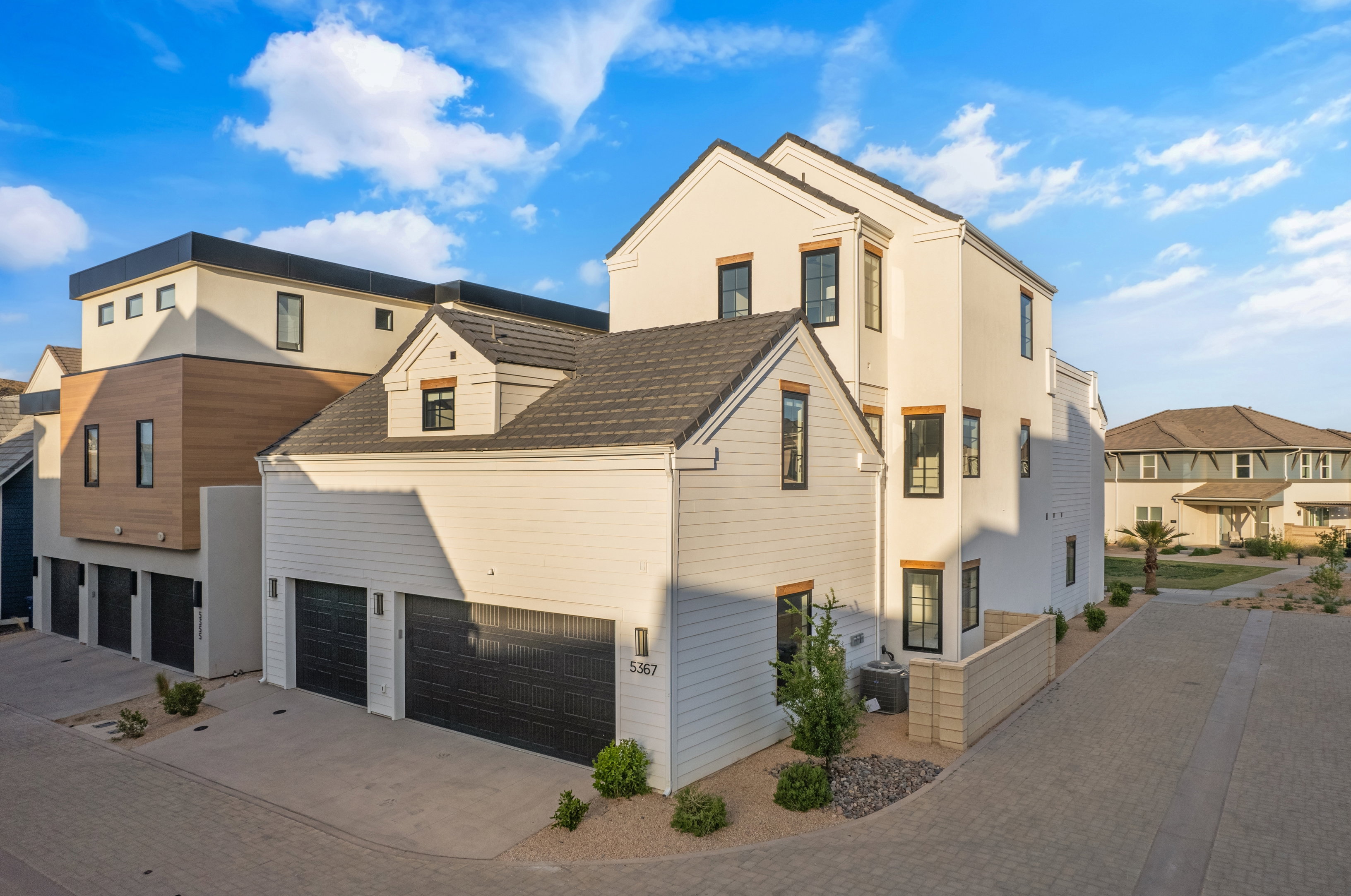 Contemporary multi-level exterior with a two-car garage, dormer window, black framed windows, and a combination of horizontal siding and smooth stucco finishes