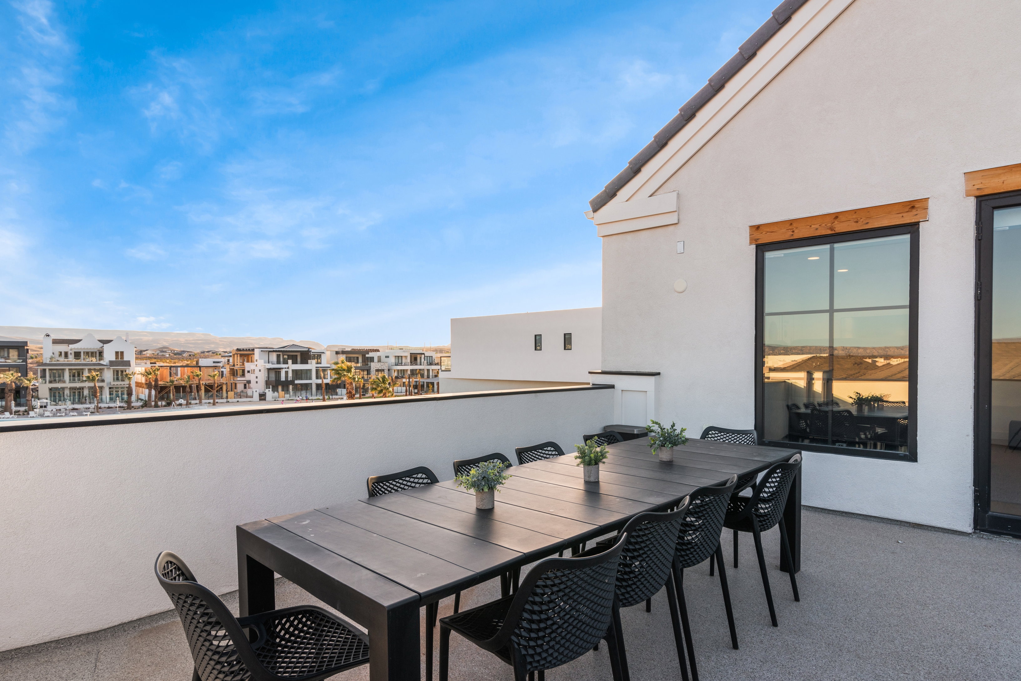 Expansive rooftop deck featuring a stucco exterior, black-framed windows with wood accents, and a dark tile roof