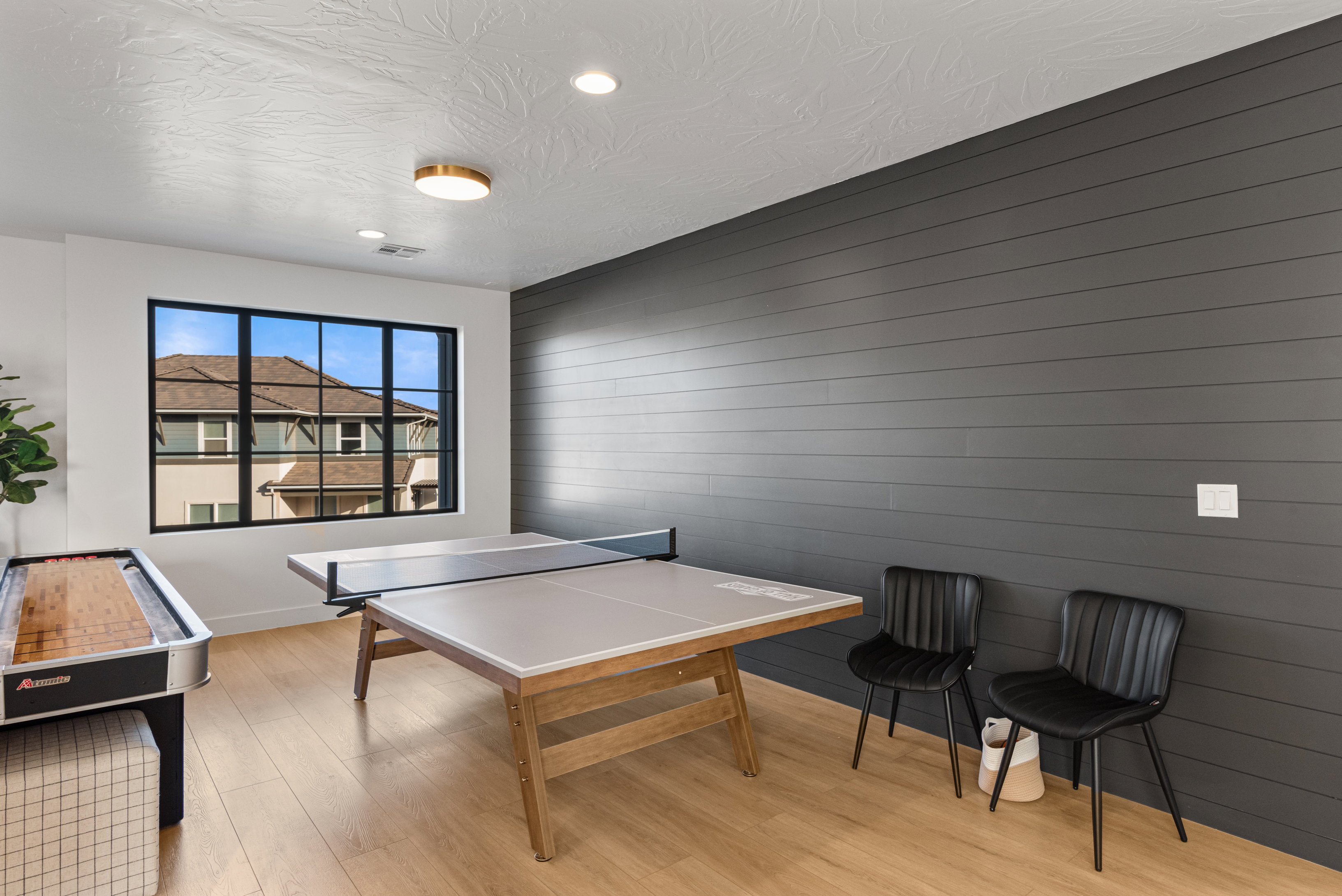 Recreation room featuring a shiplap accent wall, large multi-pane window with black trim, recessed lighting, and wood-finish flooring