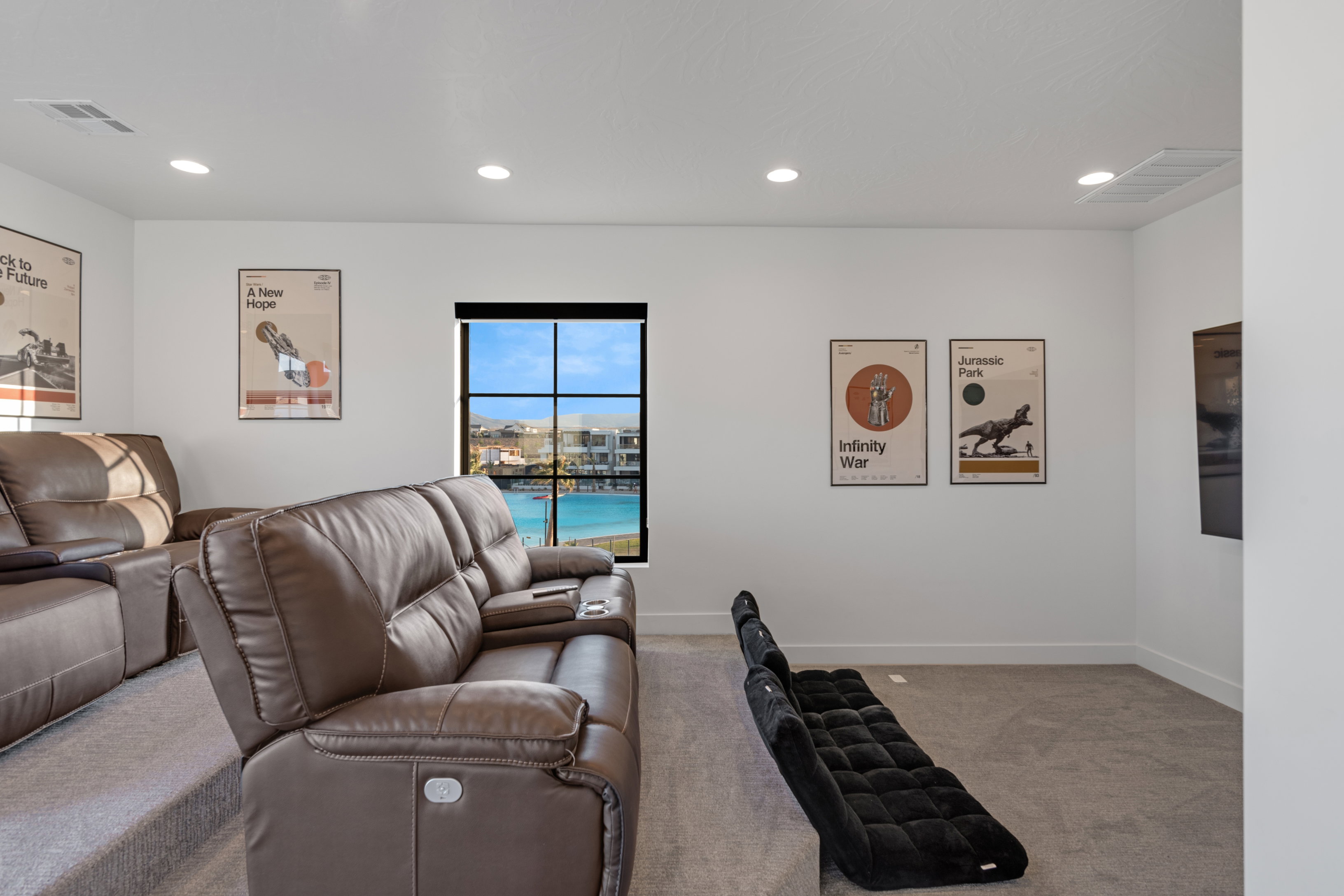 Media room featuring tiered seating, recessed lighting, and a window with a water view