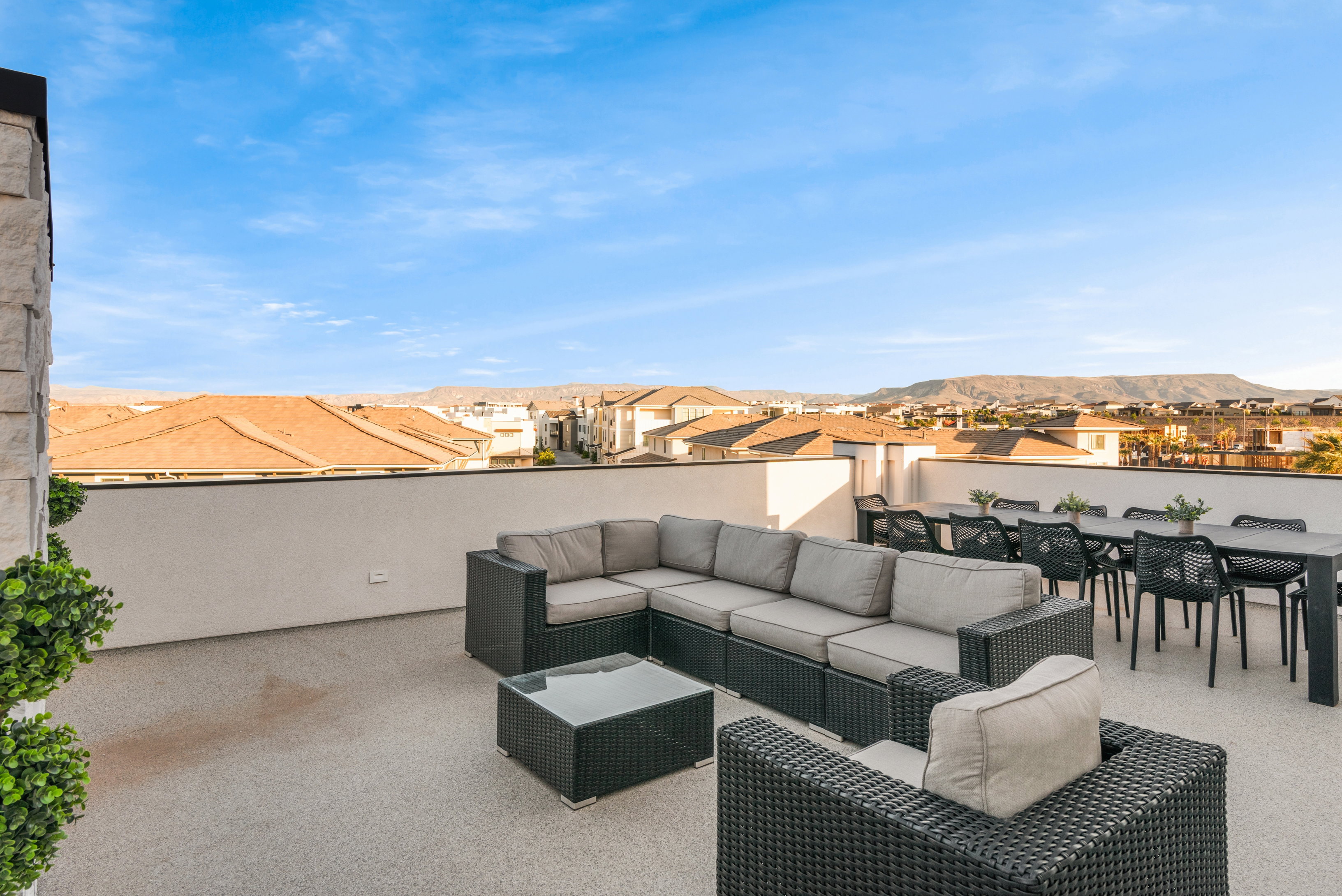 Expansive rooftop patio featuring a light-colored textured surface, a substantial perimeter wall, and a stone-clad architectural element