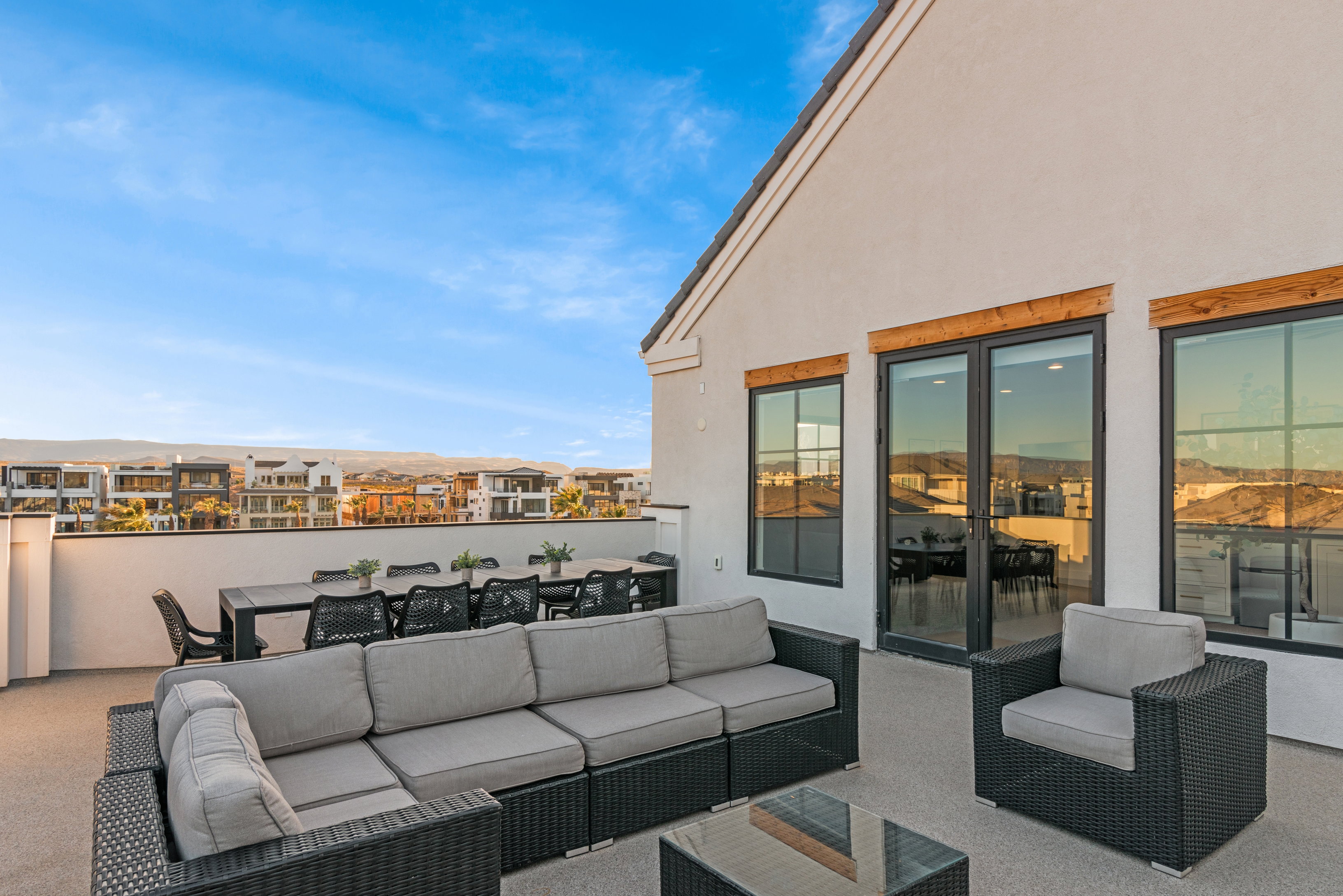 Rooftop patio with smooth stucco exterior, dark-framed windows, and a glass-paneled door