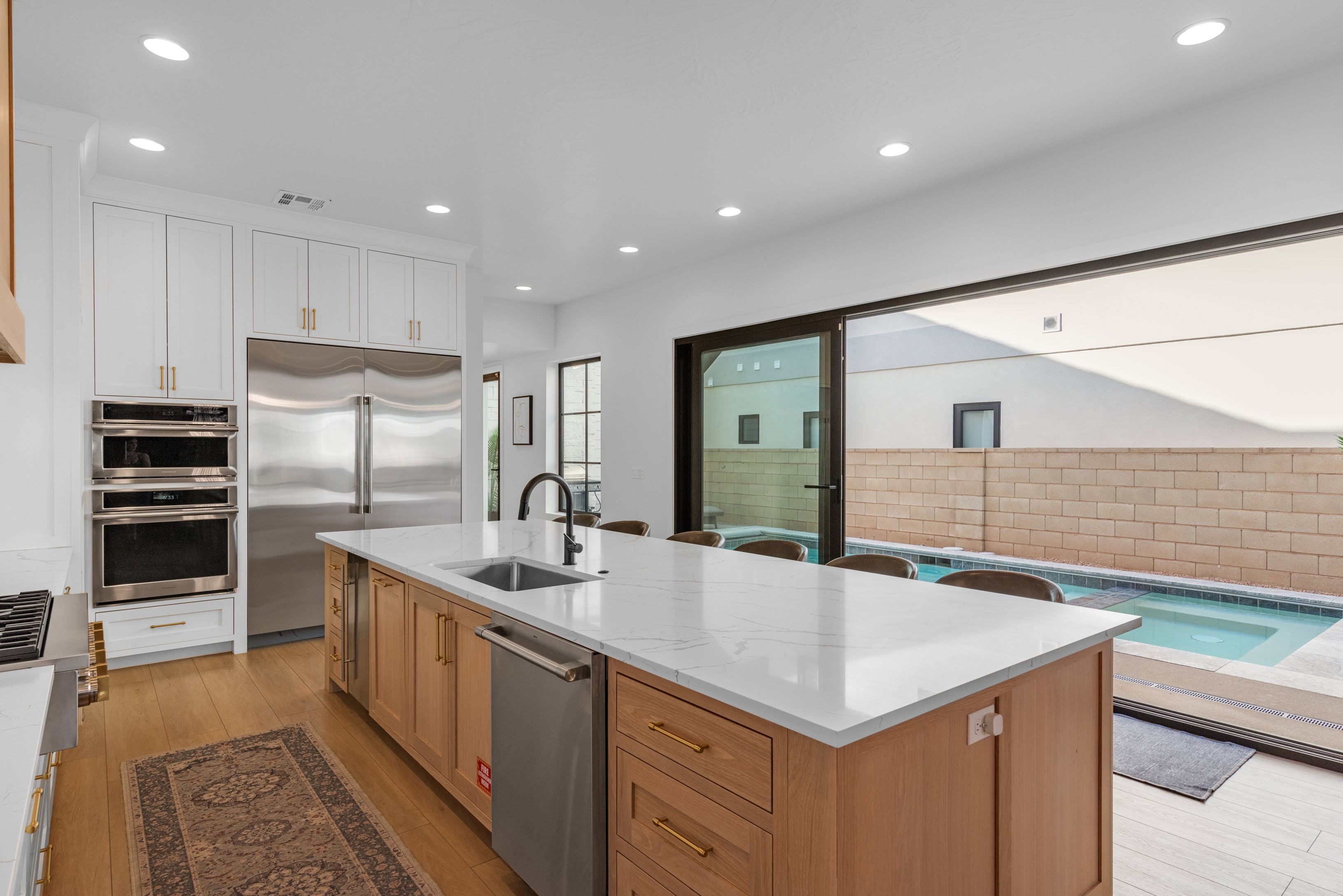 Spacious kitchen featuring a large island with a countertop, integrated sink, and seating, alongside wood-finish flooring