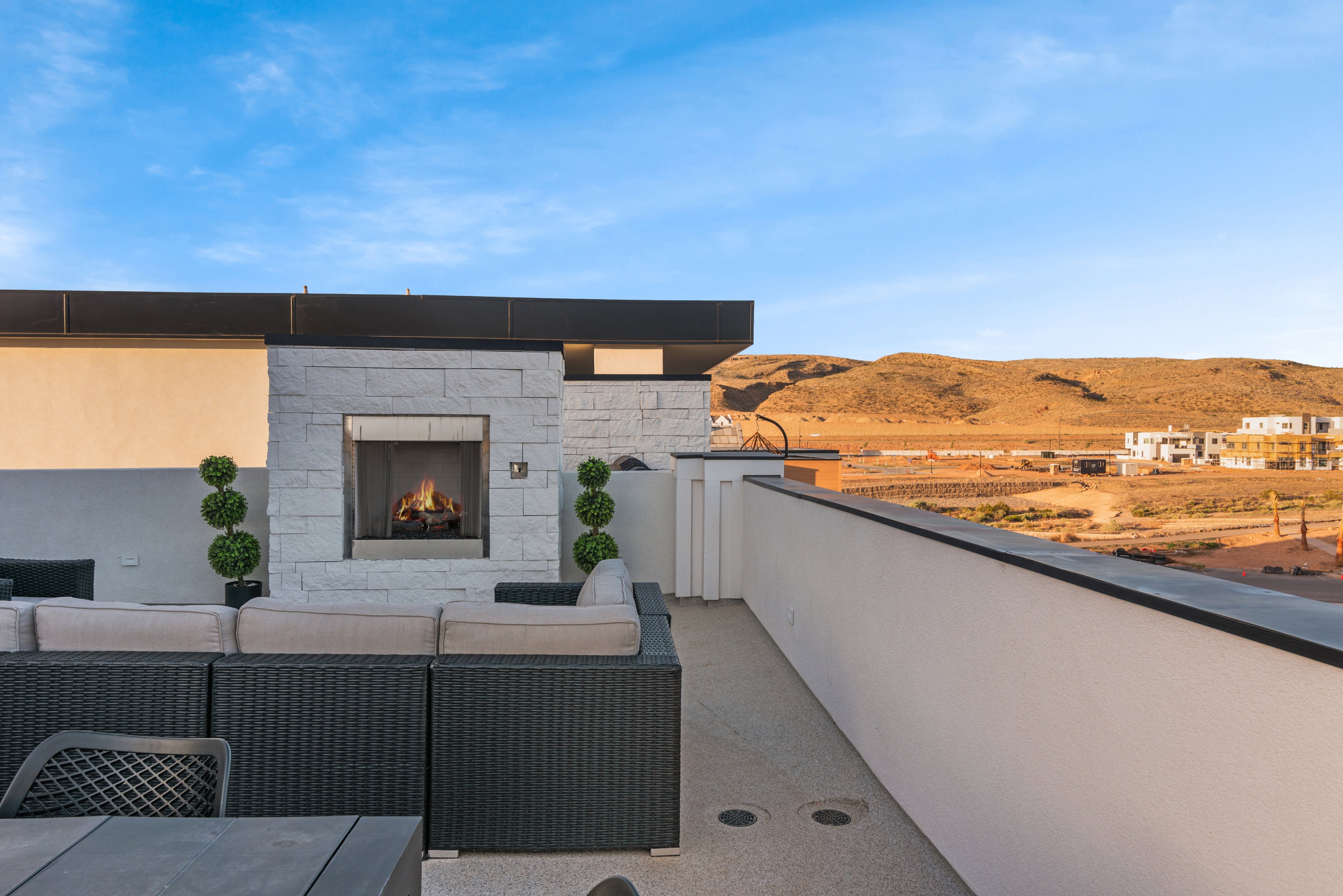 Rooftop patio with a white stone fireplace and a built-in outdoor kitchen area